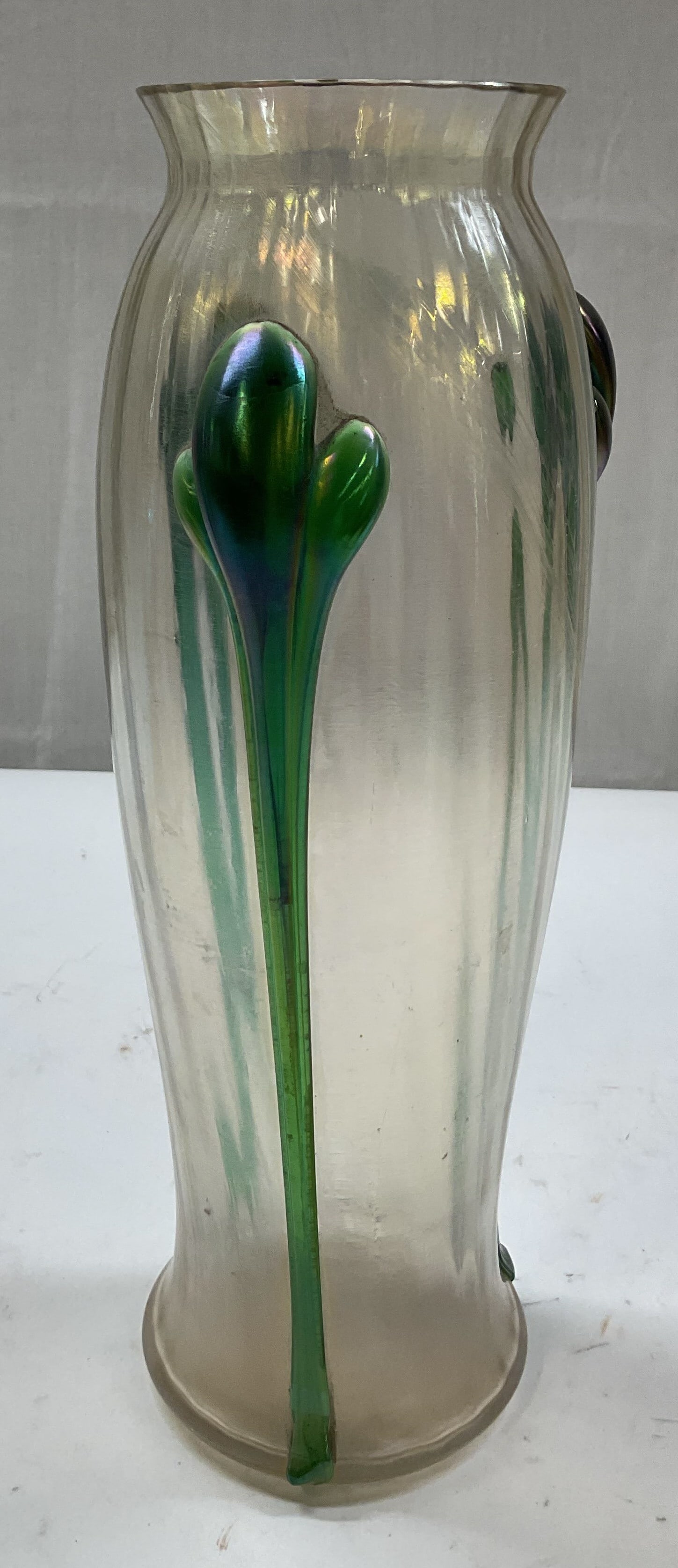 Art Nouveau Style Iridescent Art Glass Vase: Art Nouveau style iridescent art glass vase. Hand blown art glass with iridescent finish. Teardrop style green elements that flow vertically from the rim down the sides. Cylinder shape and slightly fl