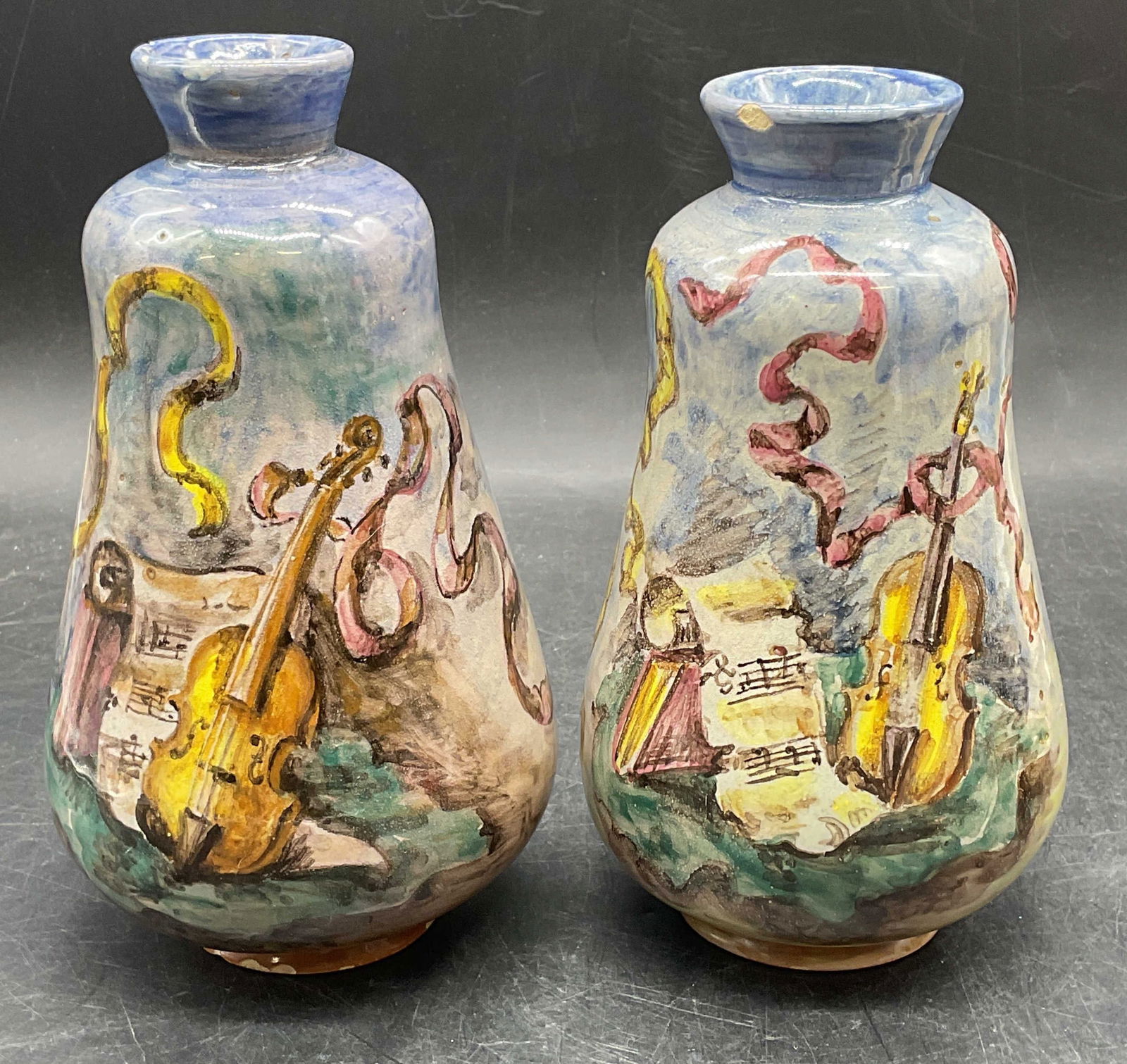 Pair Minghetti Hand Painted Ceramic Vases, Italy: Pair of Minghetti ceramic vases. Hand painted in blue with musical motifs. Violin, sheet music, candle. Signed Minghetti and marked Bologna. Made in Italy. Larger vase measures approx 4 x 7.5 inches.