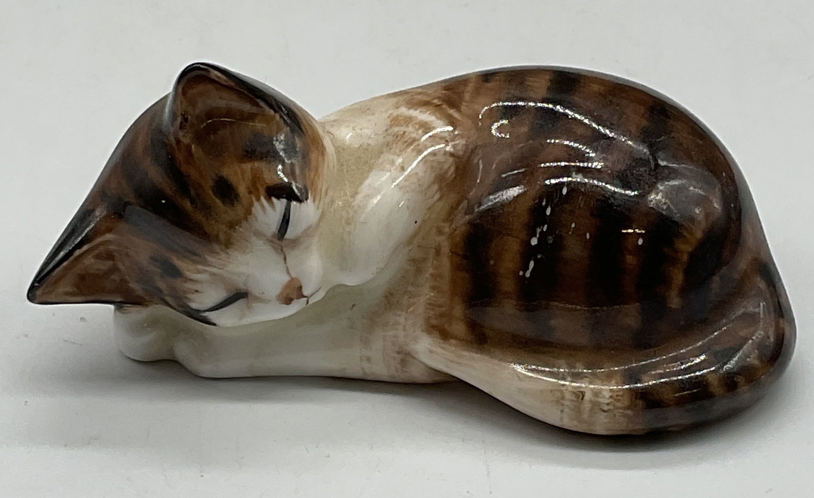Royal DOULTON Sleeping Cat China Figurine England: Royal DOULTON bone china sleeping tabby cat figurine. Signed. Made in England. Hand painted in brown and white. Measures approx 3.25 x 1.5 x 1.5 inches. Some wear consistent with exposure. Royal DOULT
