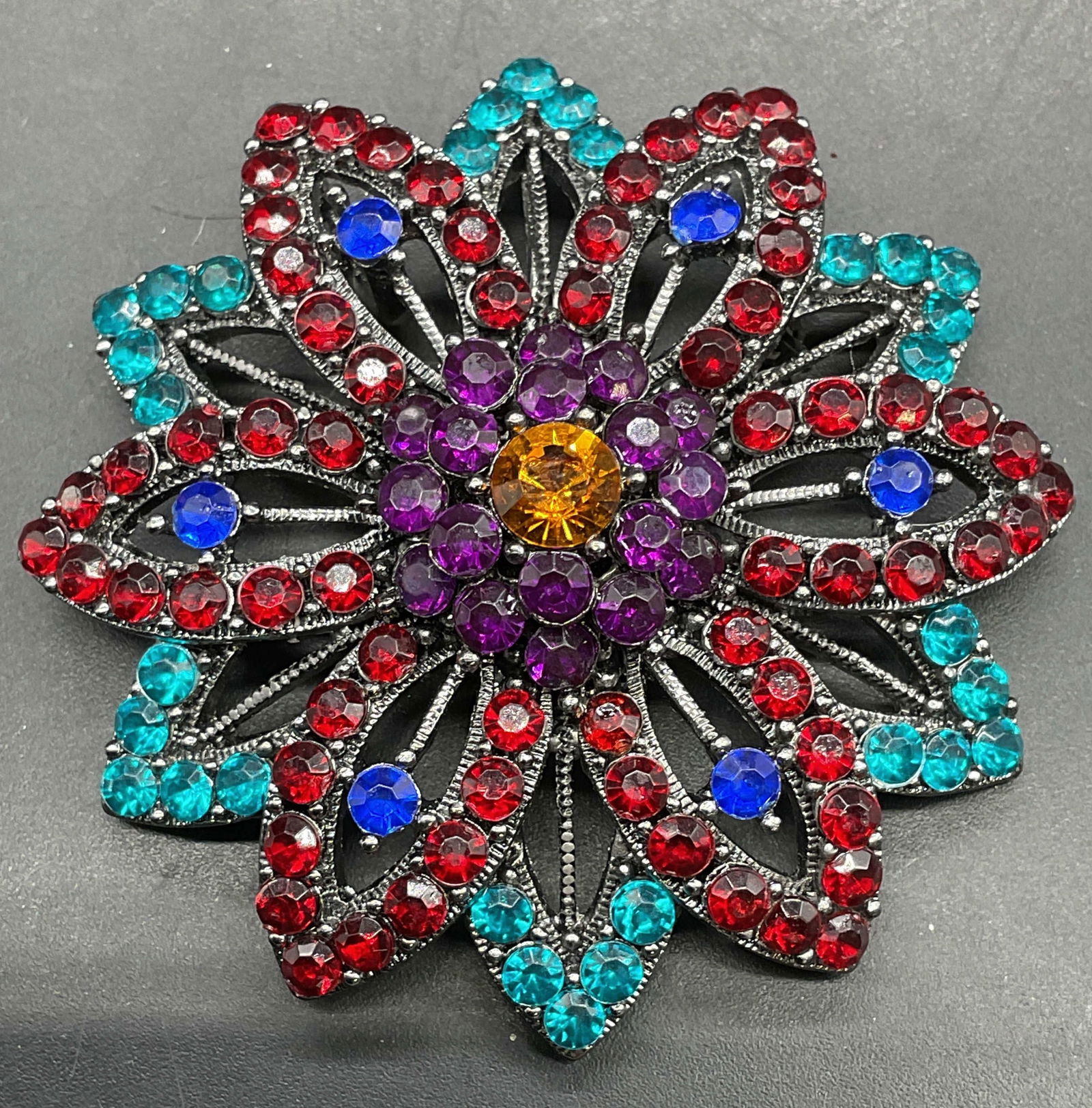 Vintage Red Blue Crystal Flower Brooch Pendant: Vintage silver tone flower brooch pendant with red, blue, and purple crystals. Measures approx 2 inches wide. Some scratching. Jewelry, estate jewelry, costume jewelry, cocktail jewelry, fashion jewel