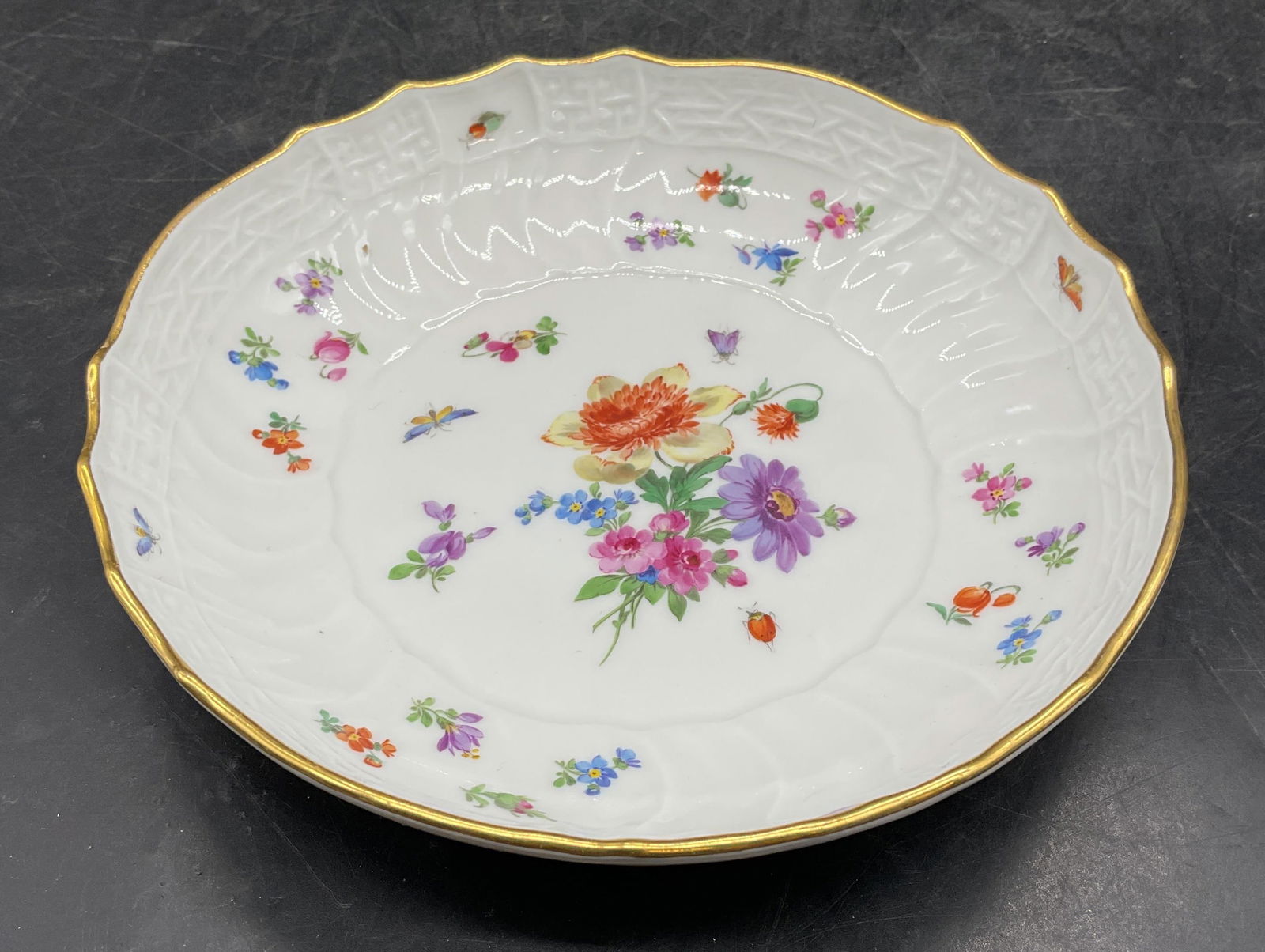 Vintage Meissen Porcelain Floral Bowl: Vintage Meissen porcelain bowl. Hand painted floral design. Gilt rim. Scalloped edge. Measures approx 6.5 x 1.5 inches. Crossed swords underglaze. Some wear consistent with exposure. Meissen