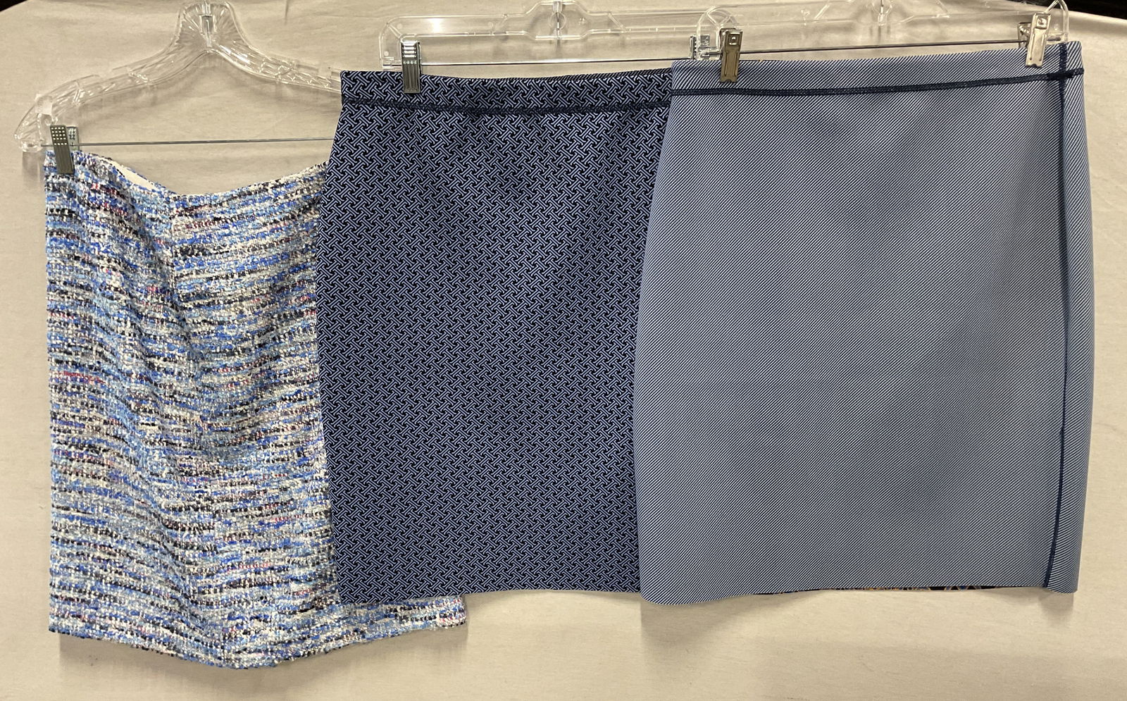 Lot 3 J. McLaughlin Blue Skirts: Lot of 3 J. McLaughlin skirts. J. McLaughlin blue abstract pattern skirt, size M, nylon material. Blue and yellow floral motif design on inside lining. J. McLaughlin blue and black abstract