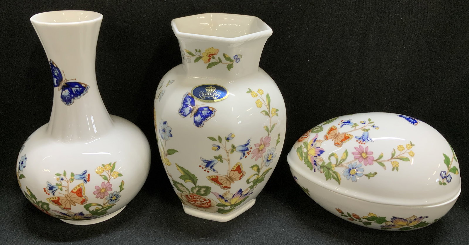 3 Aynsley Cottage Garden Vases&Trinket Box ENGLAND: Box Lot includes, 1 hexagonal bud vase, 1 bud vase & 1 egg shaped trinket box. Pieces are fine English bone china & feature a cottage garden pattern. Floral & bird motifs on body. Signed & marked on u