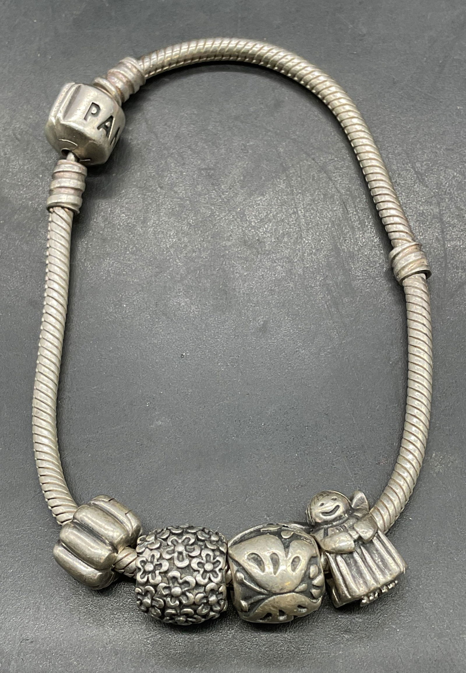 Pandora Sterling Silver Charm Bracelet: Signed Pandora sterling silver snake chain charm bracelet. Floral and angel charms. Measures approx 7 inches long. Total weight 28.6 grams. Marked sterling. Some scratching. Jewelry, estate jewelry, f