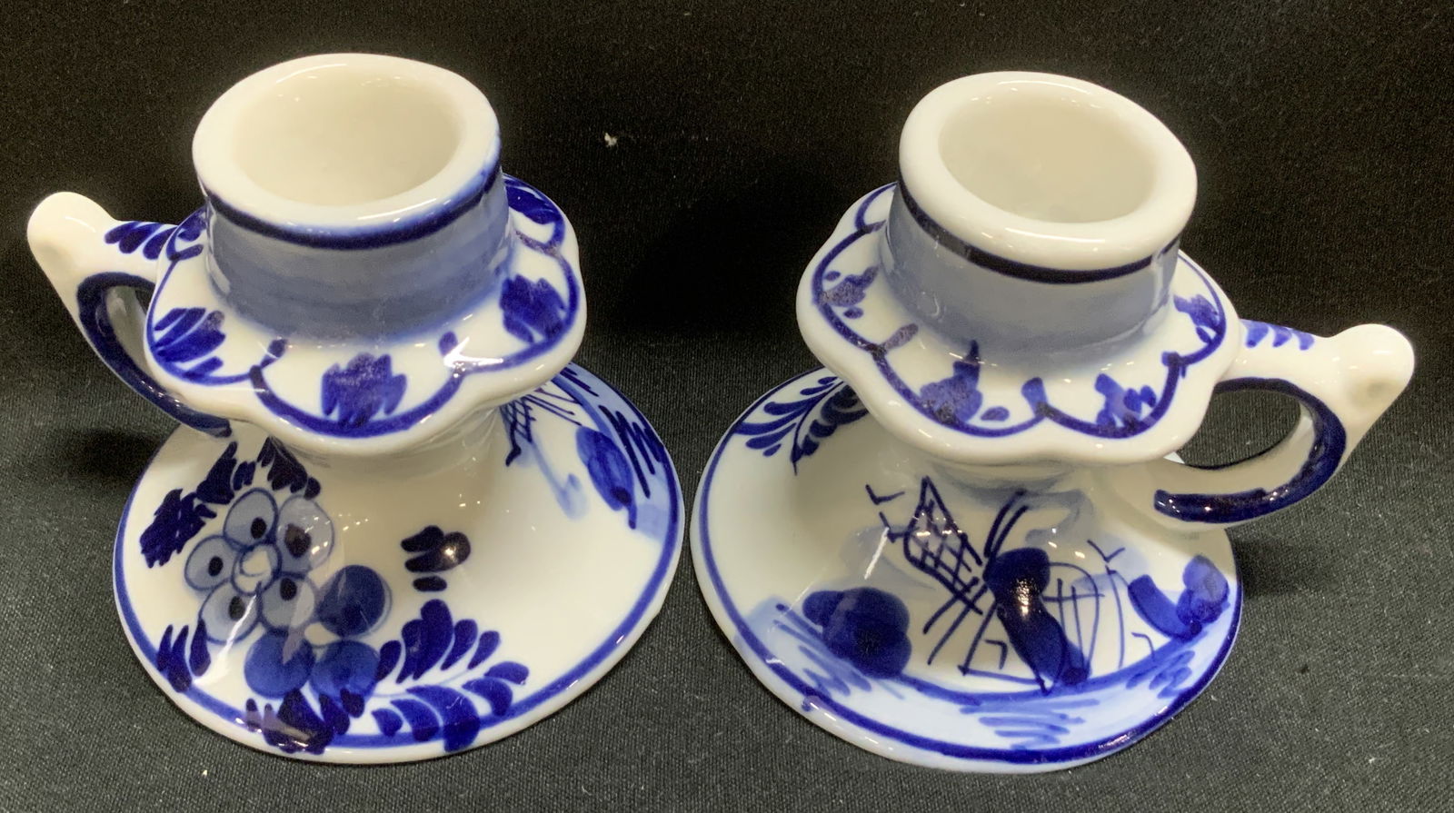 Pair Painted Delf Tsblauw Chamber Candle Holders: Lot includes, pair of vintage hand-painted chamber candle holders. Pieces have a windmill & floral design. Small handle on sides. Signed & marked on underside. Reads, HAND PAINTED. DELF TSBLAUW. 527.