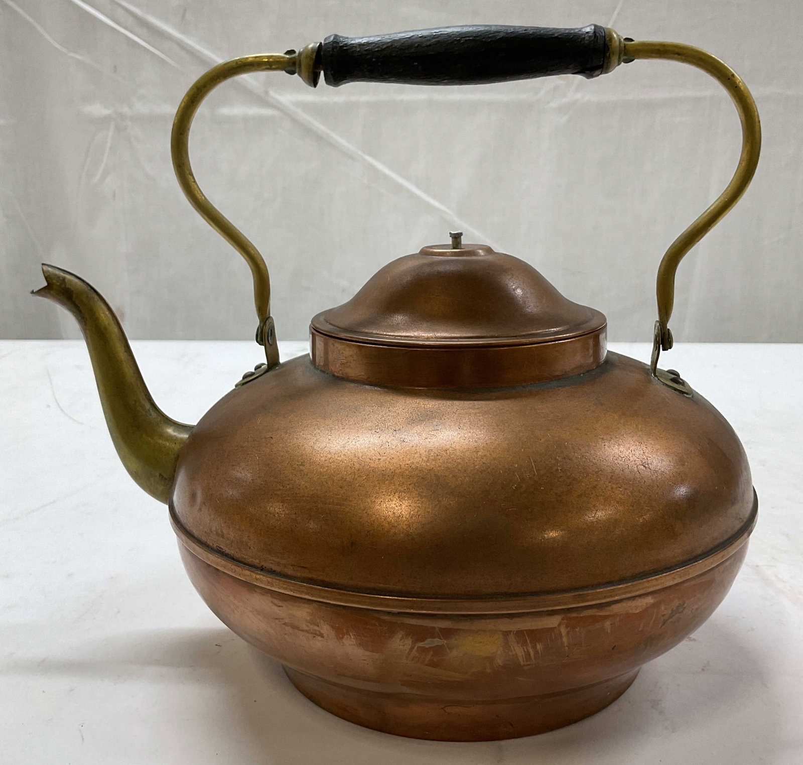 Vintage Copper Teapot Kettle W Lid Holland: Vintage copper teapot kettle with lid. Marked Holland on underside. Classic round shape with wide base. Swinging overhead handle with a dark wooden grip in center. Curved pouring spout and lid with sm