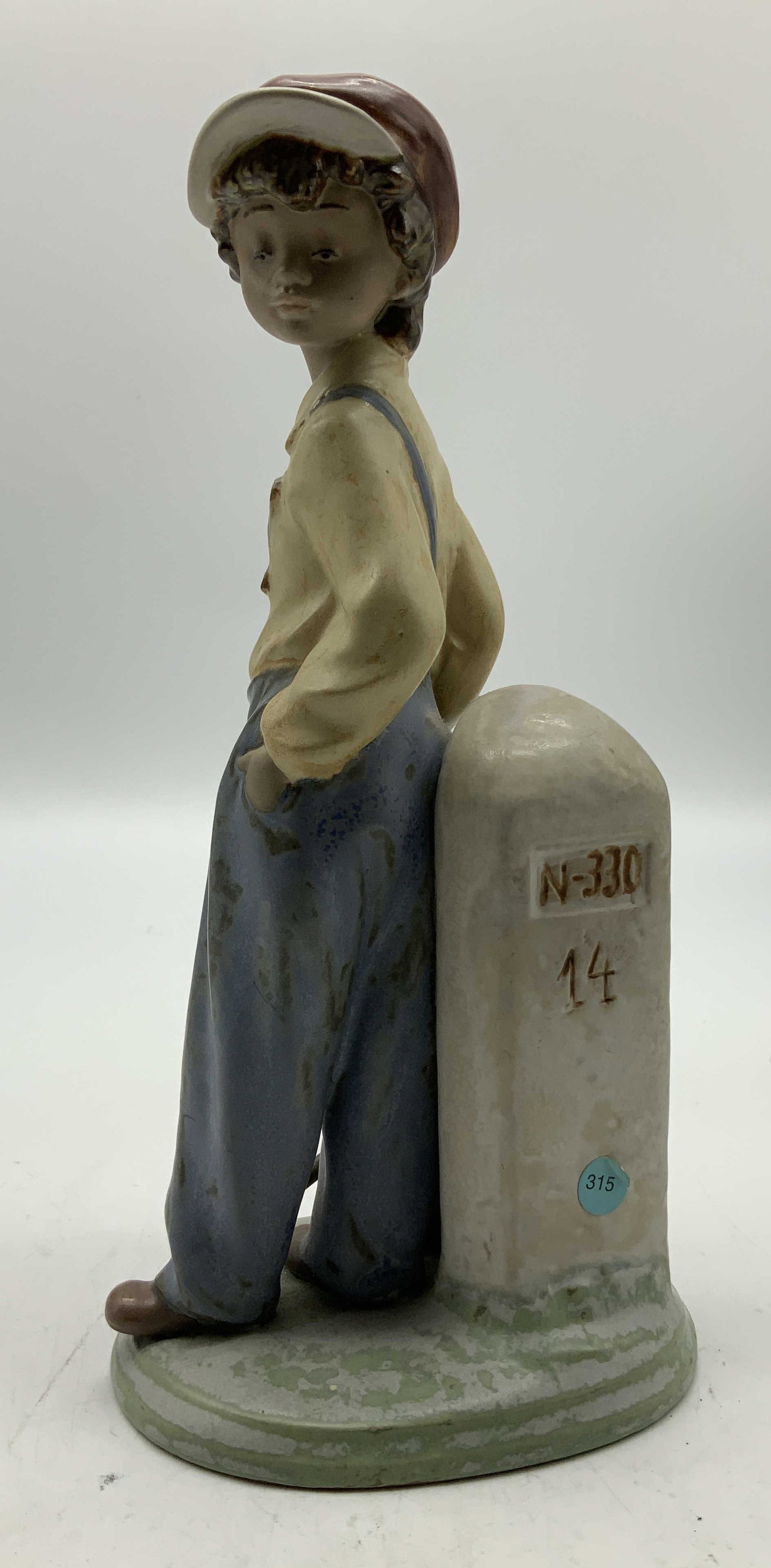 1986 Lladro The Wanderer Porc Figurine SPAIN: Porcelain figurine depicts a young boy wearing a yellow shirt & blue plants. He is resting by a roadside marker. Shades of green, blue, yellow, red, grey. Property of opera singers estate from the ren