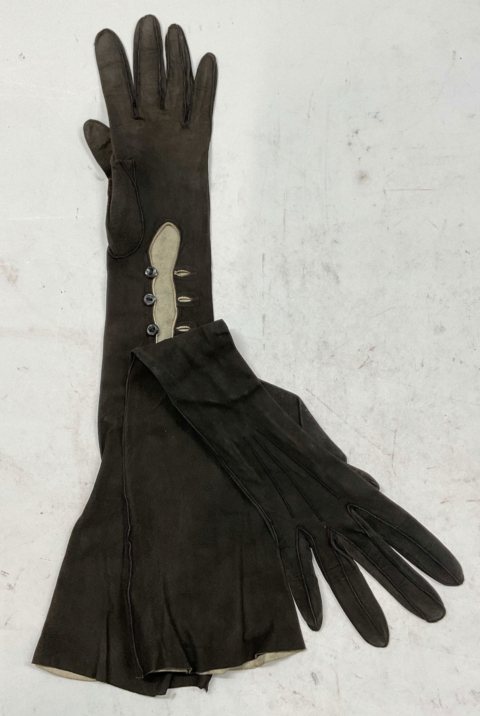 Vintage Brown Buttoned Suede Opera Gloves: Vintage brown buttoned suede opera length gloves. Feels like suede. Stiching around fingers. Button accent. Measures approx 4 x 18 inches. Wear consistent with exposure. Property of opera singers