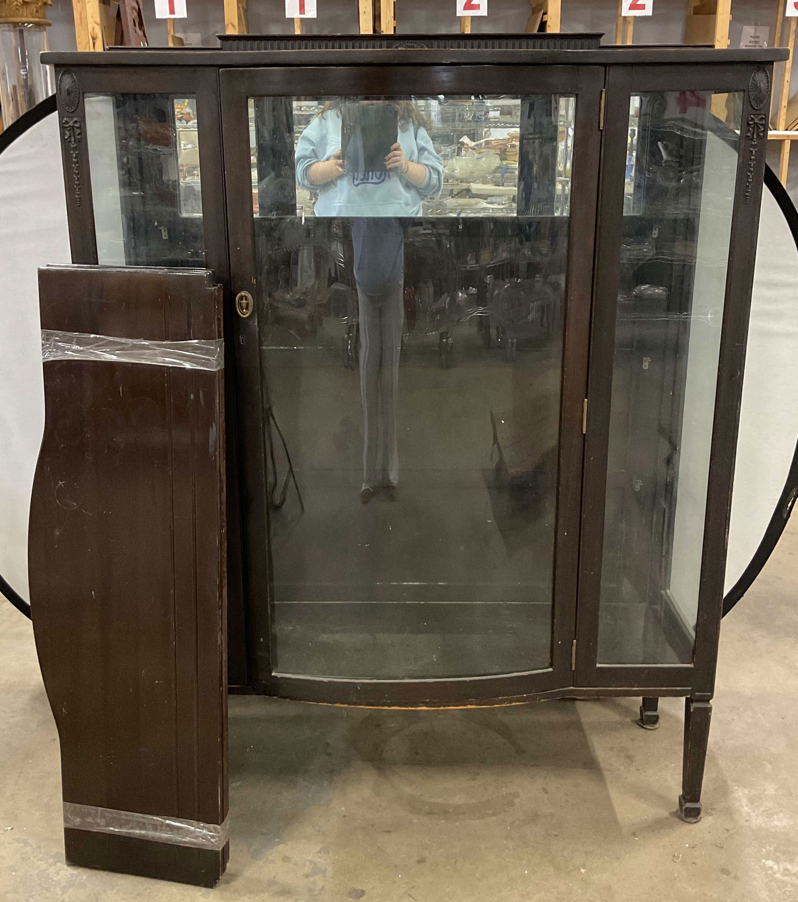 Vintage Wooden Glass China Cabinet: Vintage wooden glass china cabinet. Curved surfaces on top and bottom. Wooden frame. Glass door that opens. Ornate carved designs. Ribbed texture. Comes with shelving unit. Measures approx 15 x 47 x 5