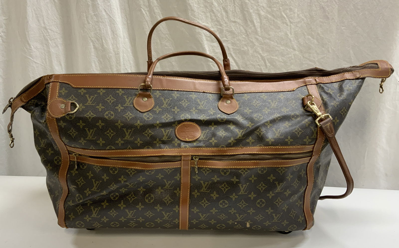 Brown Leather Luggage Bag: Brown monogram leather rolling luggage bag. Zippered compartments to outer and interior. Measures approx. 23 x 10 x 11 inches. Wear to leather including scratching and blemishes observed. luggage bag,