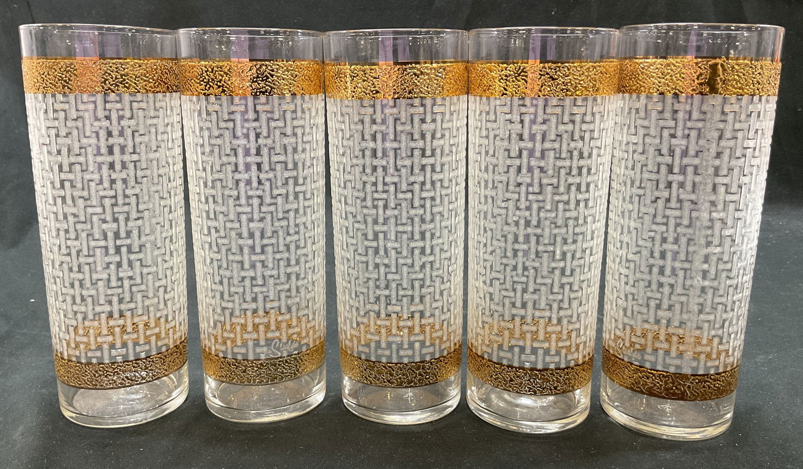 Set 5 Starlyte Gilt High Ball Glasses: Set of 5 Starlyte gilt decorated high ball glasses. Gilt decorated bands on top and bottom. Geometric embossed basketweave pattern. Measures ht approx 7 inches diam approx 2 1/2 inches. Surface wear c