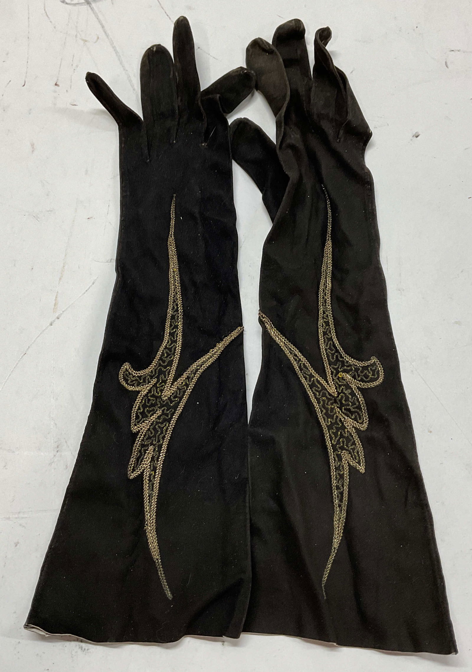 French Vintage Hand Embroidered Suede Opera Gloves: French vintage hand embroidered suede opera gloves. Black suede opera gloves. Inside label says made in France. Ornate hand stitched design. Gilded threads. Gloves read size 7. Wear consistent with ex