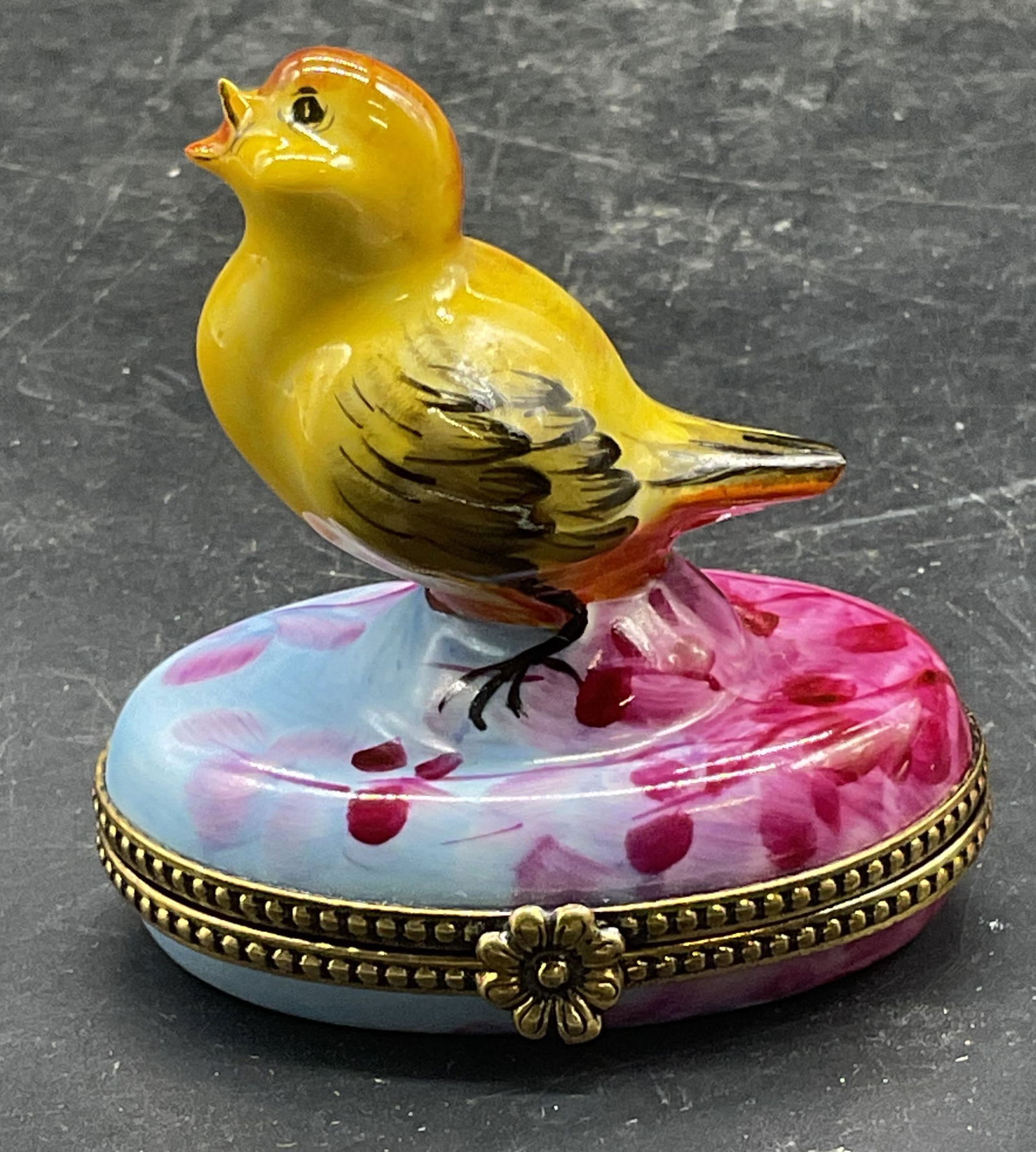 Limoges Porcelain Yellow Bird Trinket Box, France: Limoges porcelain trinket box with bird motif. Hand painted yellow, blue, and purple. Signed. Made in France. Measures approx 2.25 x 1.5 x 1.25 inches. Some scratching. Limoges trinket box,