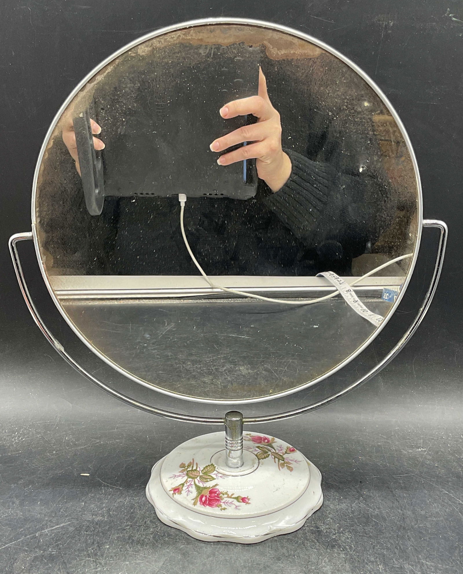 Vintage Porcelain Footed Spinning Vanity Mirror: Vintage standing vanity mirror with spinning magnified mirror. Floral design on porcelain base. Measures approx 11.25 x 13.25 inches. Wear including scratching and residue. Vanity mirror, mirror,