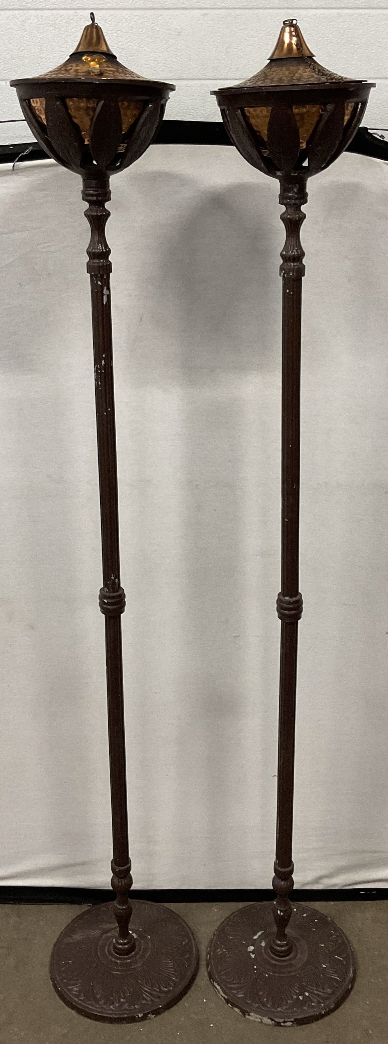 Pair Copper Brown Metal Standing Oil Lamps 64in: Pair of brown painted metal standing oil lamps with copper bowls. Slender columns with wide round bases and decorative floral design. Measure approx 10.5 x 64 inches. Wear including scratching