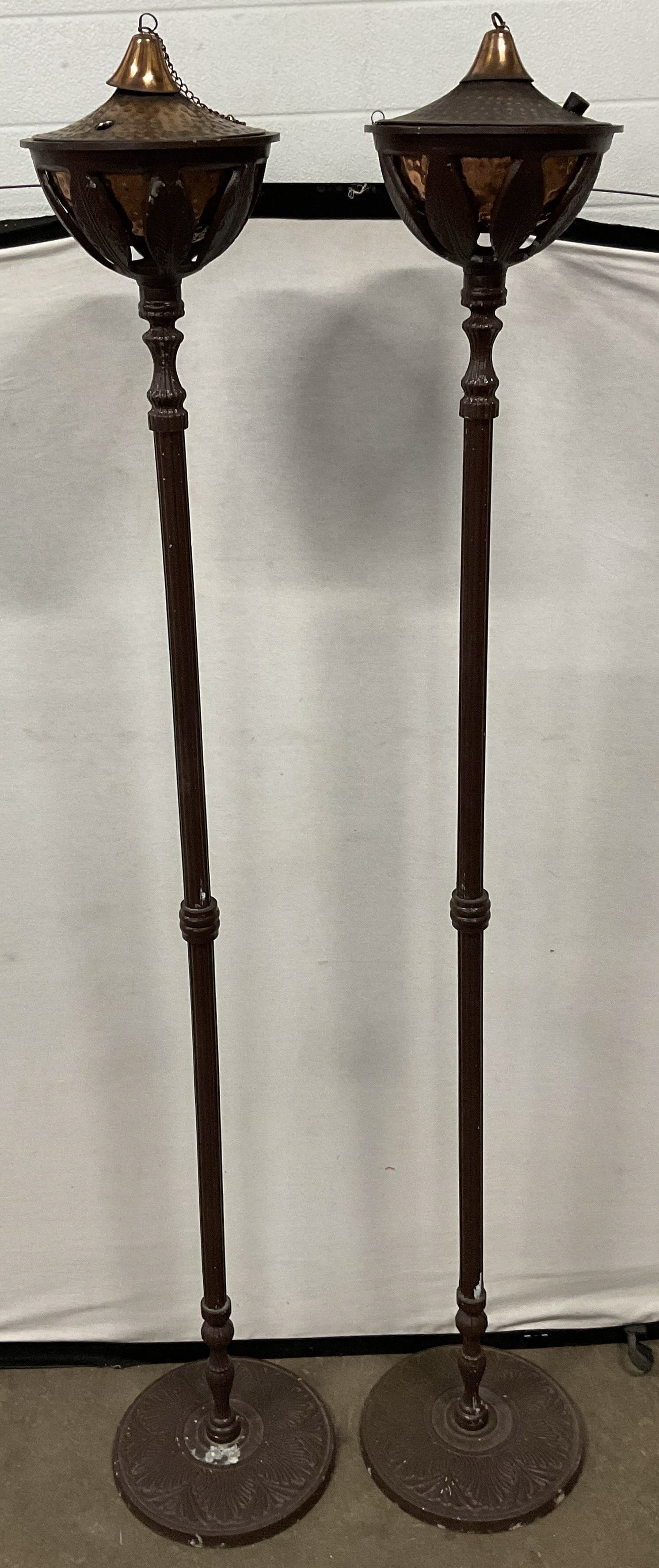 Pair Copper Brown Metal Standing Oil Lamps 64in: Pair of brown painted metal standing oil lamps with copper bowls. Slender columns with wide round bases and decorative floral design. Measure approx 10.5 x 64 inches. Wear including scratching
