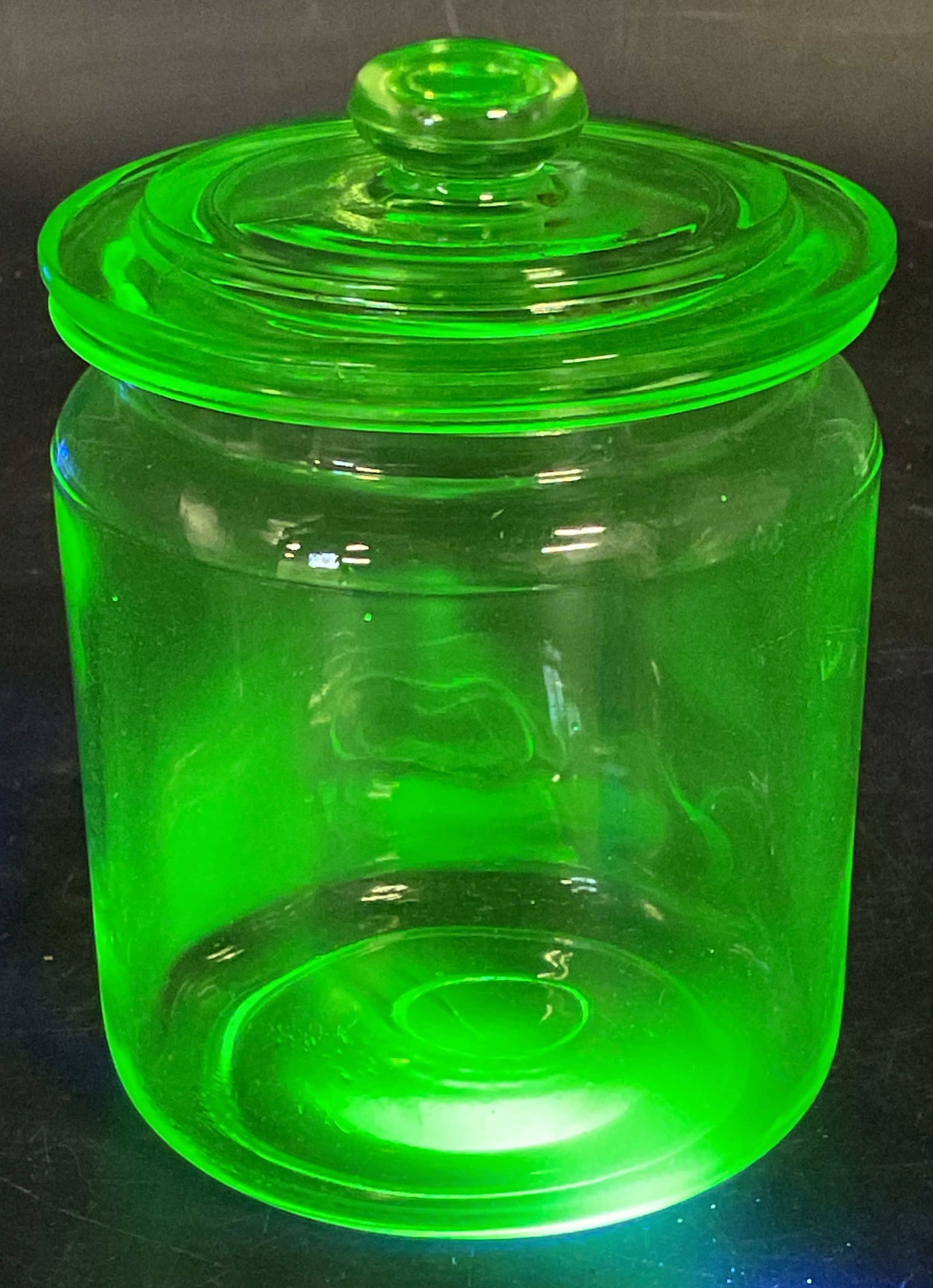 Vintage Uranium Glass Lidded Jar: Vintage uranium glass jar with lid. Cylindrical bowl and lid with raised handle. Measures approx 3.75 x 5 inches. Glass is UV light reactive. Some scratching. Uranium glass, uranium glass jar,