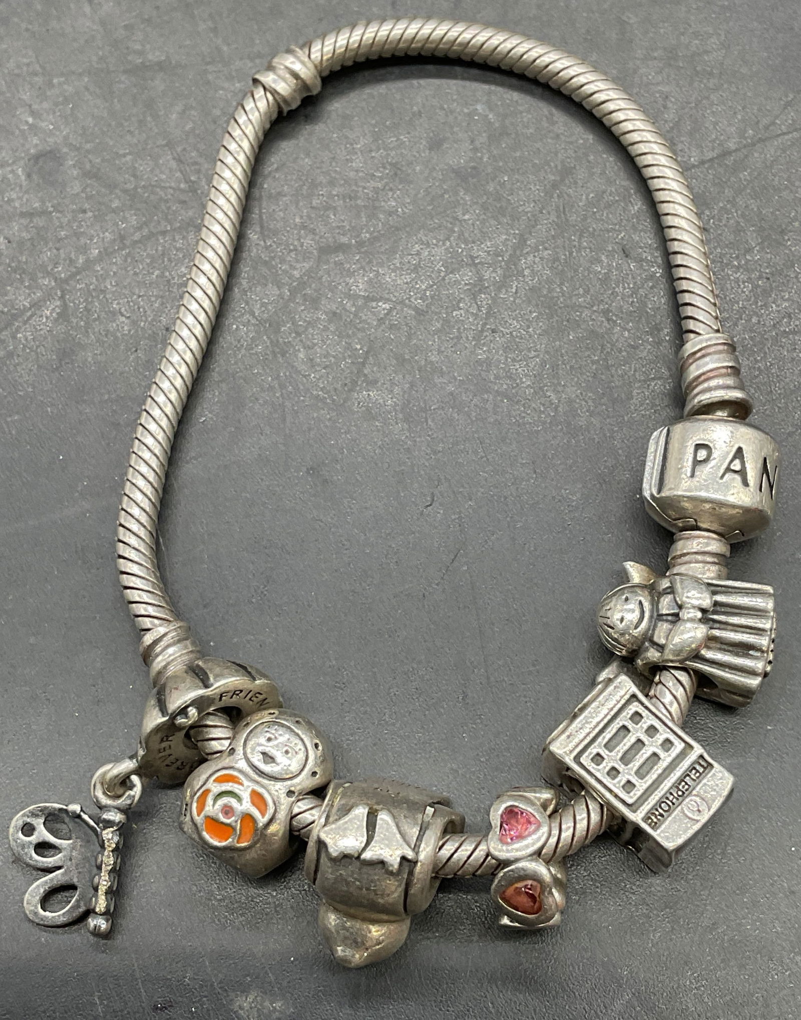 Pandora Sterling Silver Charm Bracelet: Signed Pandora sterling silver charm bracelet. Sterling and semiprecious charms, heart, butterfly, telephone booth, bird, figure. Marked sterling. Measures approx 6.5 inches long. Total weight 33.5 gr