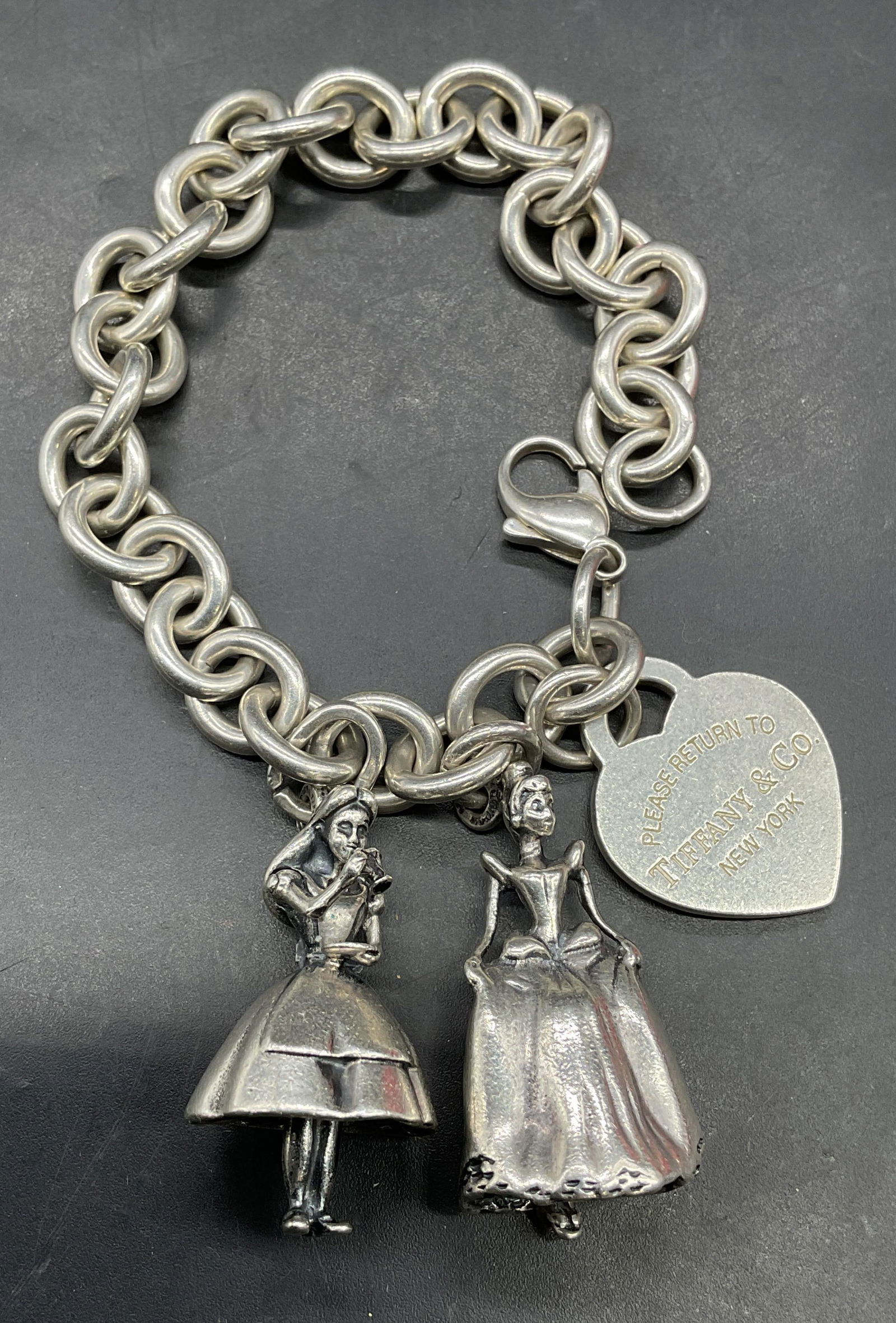 Tiffany Sterling Silver Cinderella Charm Bracelet: Tiffany & Co Sterling silver bracelet with classic heart tag and Disney Cinderella and Alice in Wonderland charms. Signed and marked sterling. Measures approx 7.5 inches long. Total weight 56.1 grams.
