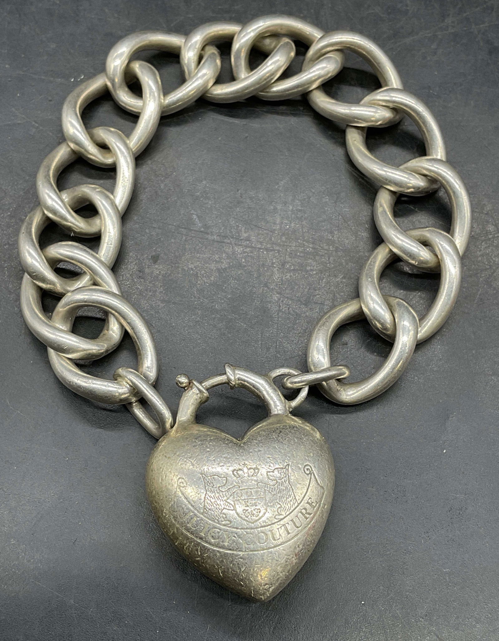 Juicy Couture Sterling Silver Heart Bracelet: Signed Juicy Couture sterling silver chain bracket with heart locket motif charm. Measures approx 7.5 inches long. Marked sterling. Total weight 47.8 grams. Some scratching. Jewelry, estate jewelry, f