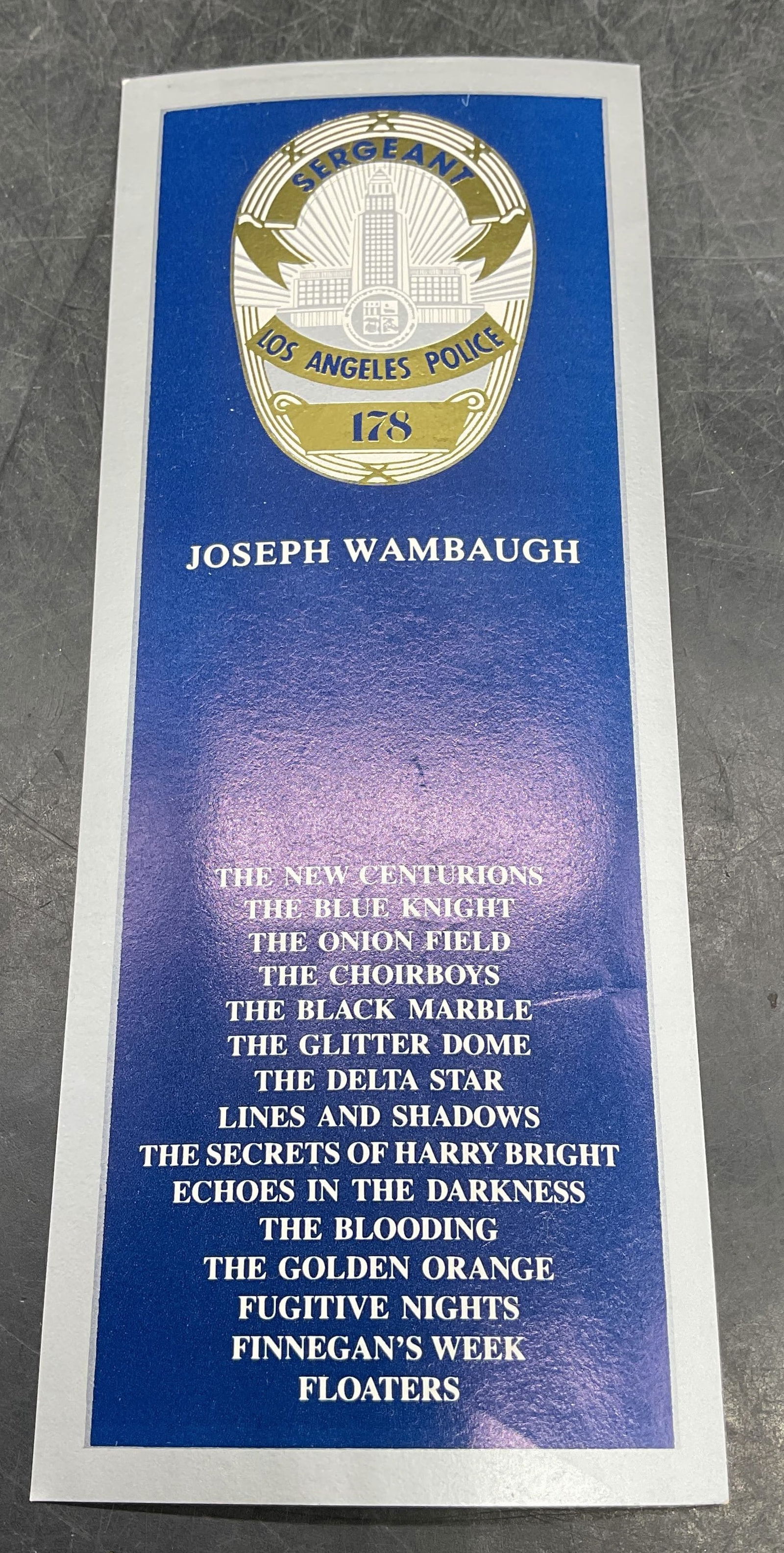 Signed Joseph Wambaugh (1937-2025) Bookmark: Bookmark signed by Joseph Wambaugh (1937-2025). Signed and inscribed by Wambaugh on reverse in ink, dated 1989. Front features Los Angeles Police Department motif with list of books written by the aut