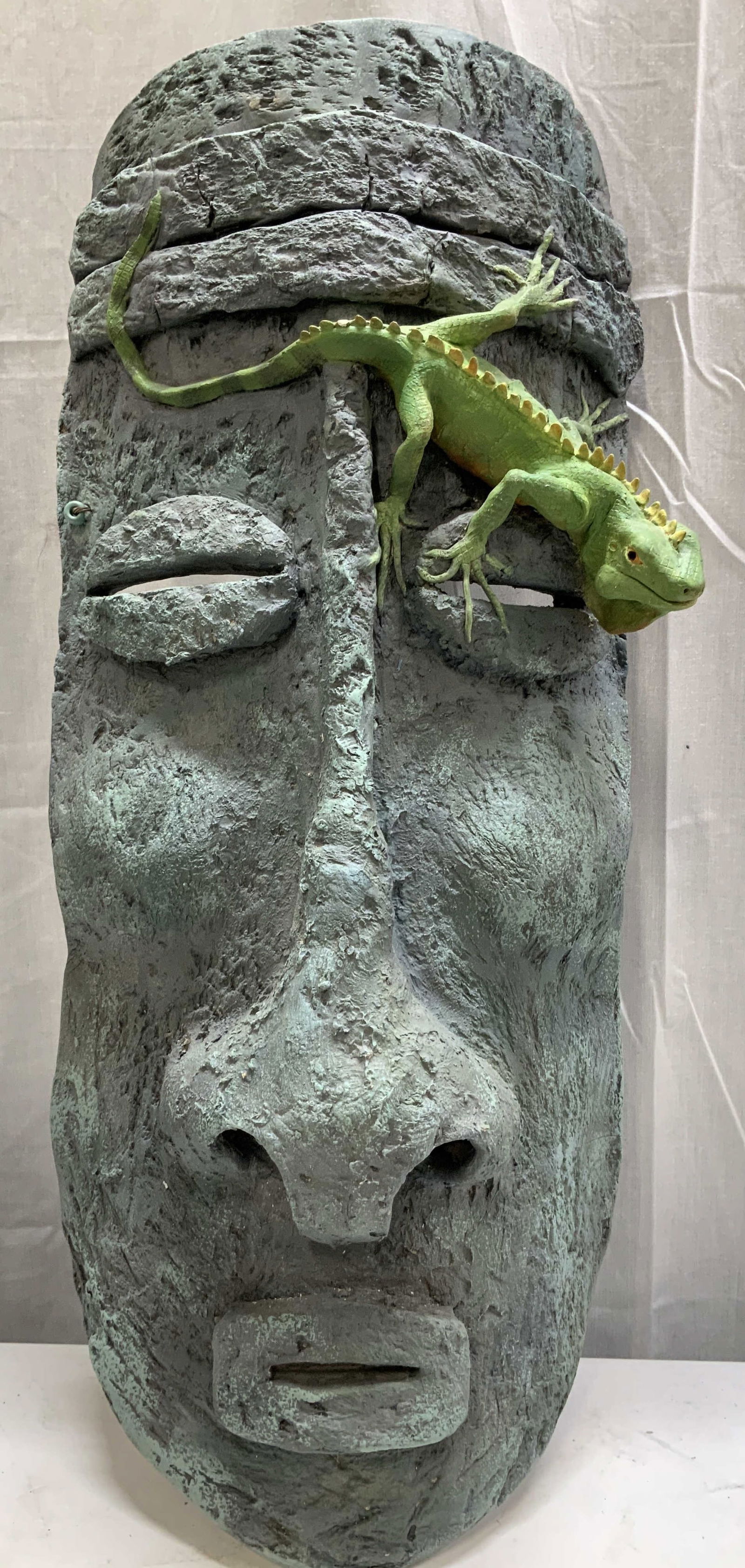 Sgnd Tribal Style Mask W Lizard Wall Sculpture: Tribal style sculptural wall mask features elongated facial proportions, layered headband accent & a green lizard perched on eye. Sculpture is green toned & has textured finish. Ceramic material. Sign