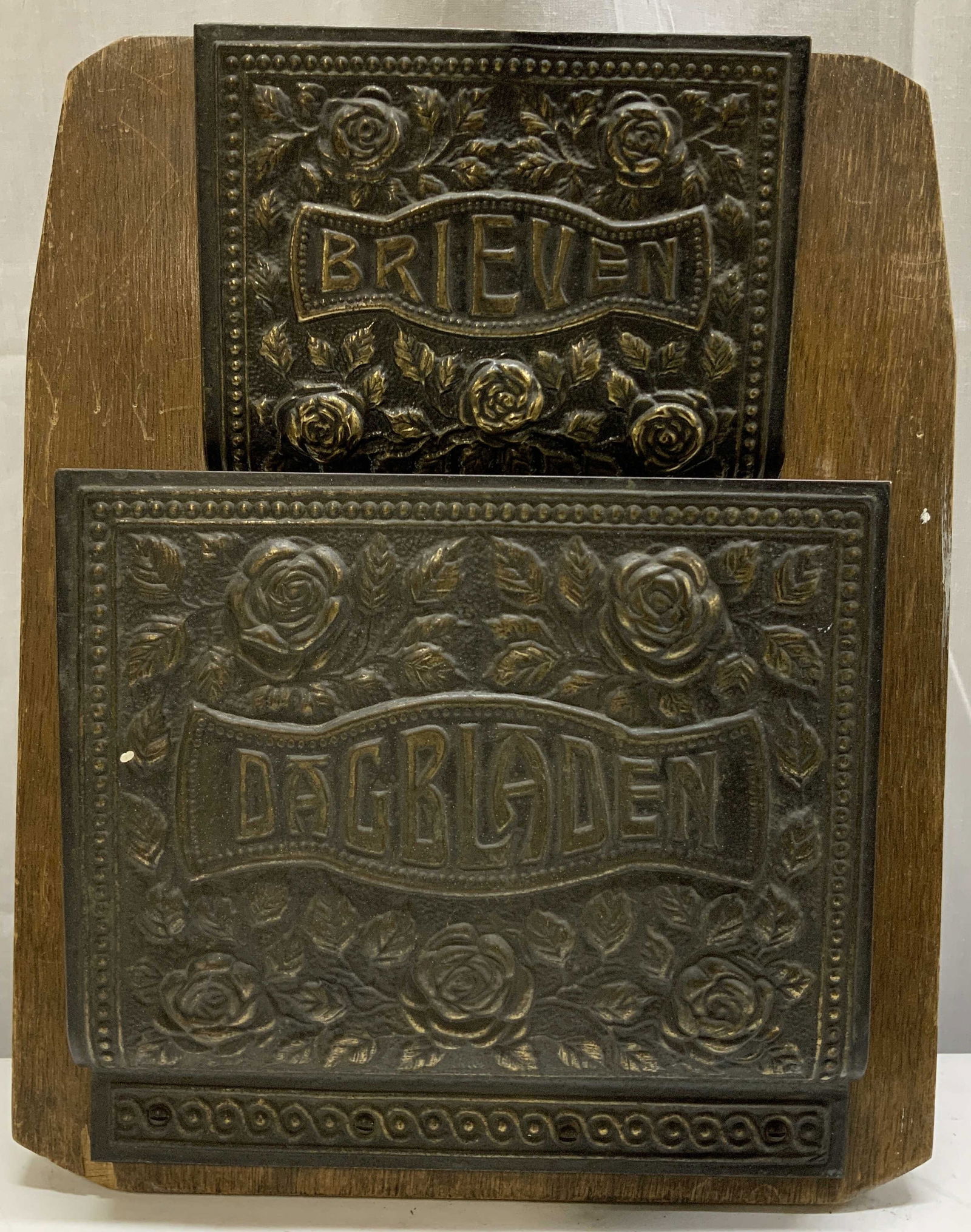 Antique Double Brass Letter Holder Wall Mount: Antique double brass letter holder mounted on a wooden plaque. Embossed rose motif with text in Dutch that reads, DAGRIGDEN: Newspapers & Brieven: Letters. Surface wear consistent to age, use & exposu