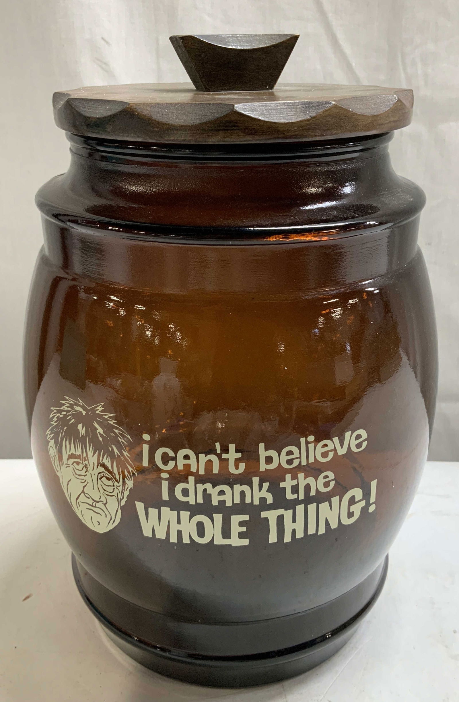 Vtg Siesta Ware Brown Glass Lidded Cookie Jar: Vintage Siesta Ware brown glass cookie jar w a wooden lid & I cant believe I drank the WHOLE THING! text on body. Signed & marked on underside. Reads, SIESTA WARE. Surface wear consistent to age, use