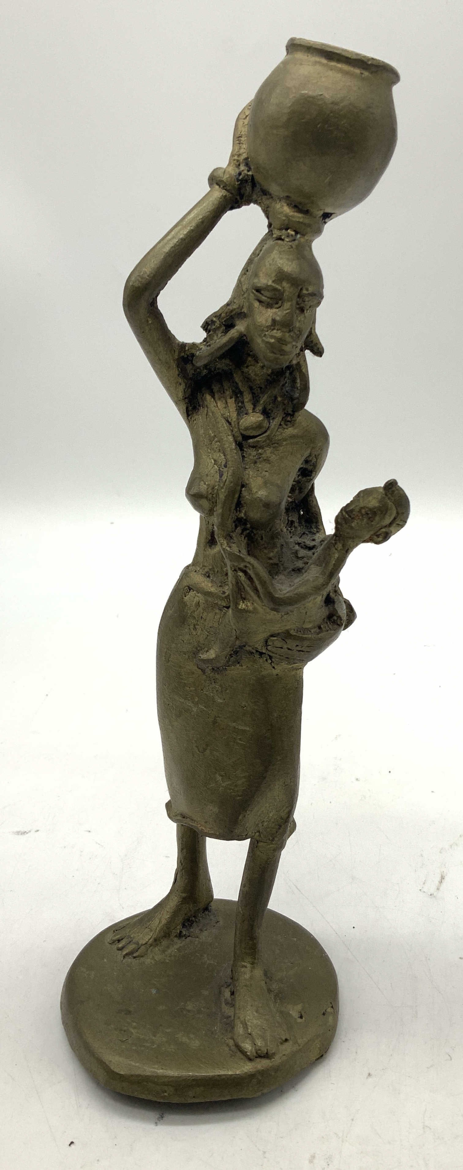 Vtg African Women Carrying Child Brass Fig: Vintage African figurine of a woman. She is balancing a basket/pot on her head & is holding a baby on her left. Fig is standing on base. Piece is brass material. Surface wear consistent to age, use &