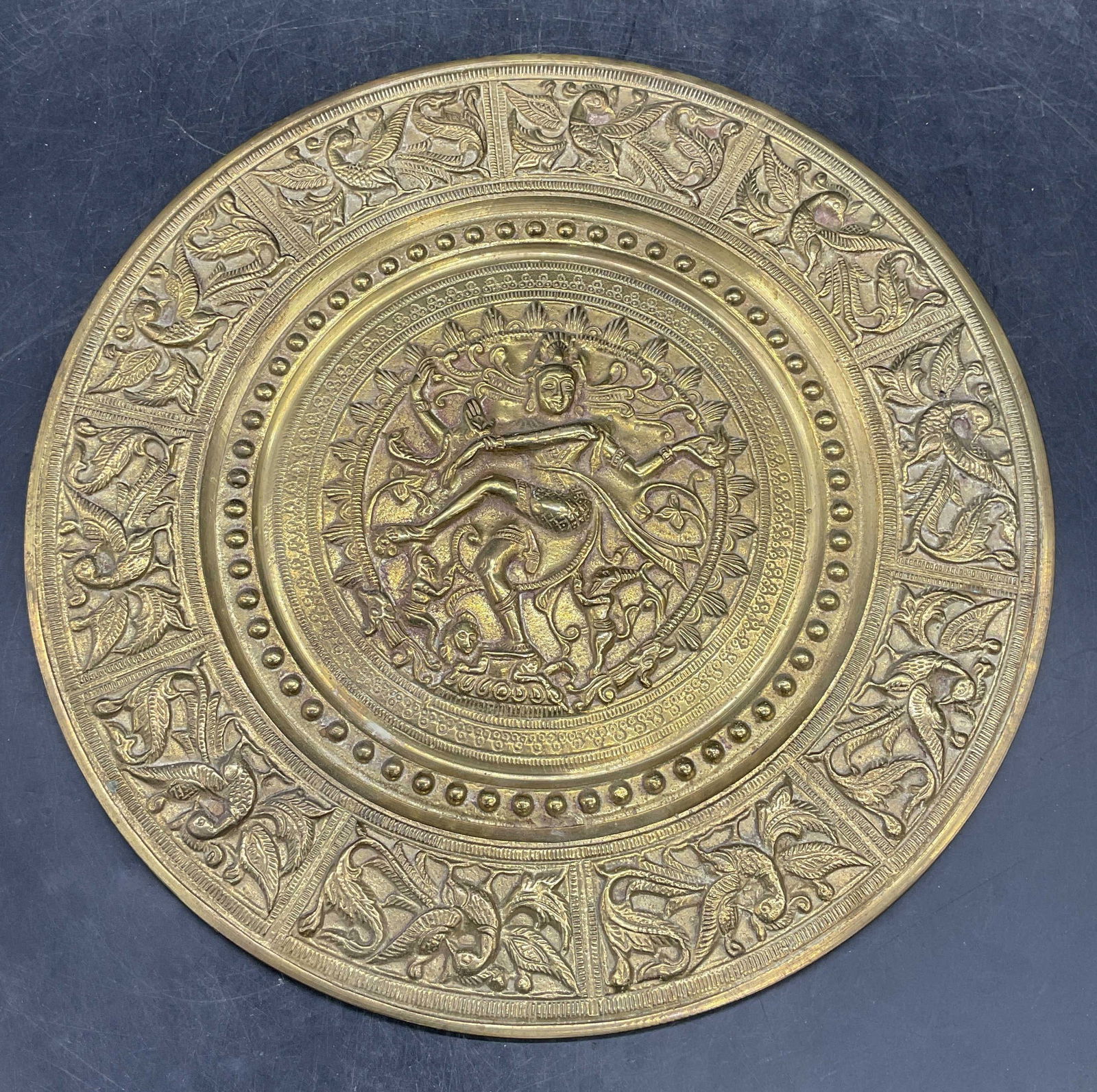Shiva Nataraja Brass Wall Plate Plaque: Brass wall plate plaque with Shiva Nataraja design and bird border. Measures approx 10.25 inches wide. Plaque has weight. Some scratching. Wall plaque, brass plaque, shiva Nataraja plaque, shiva plaqu