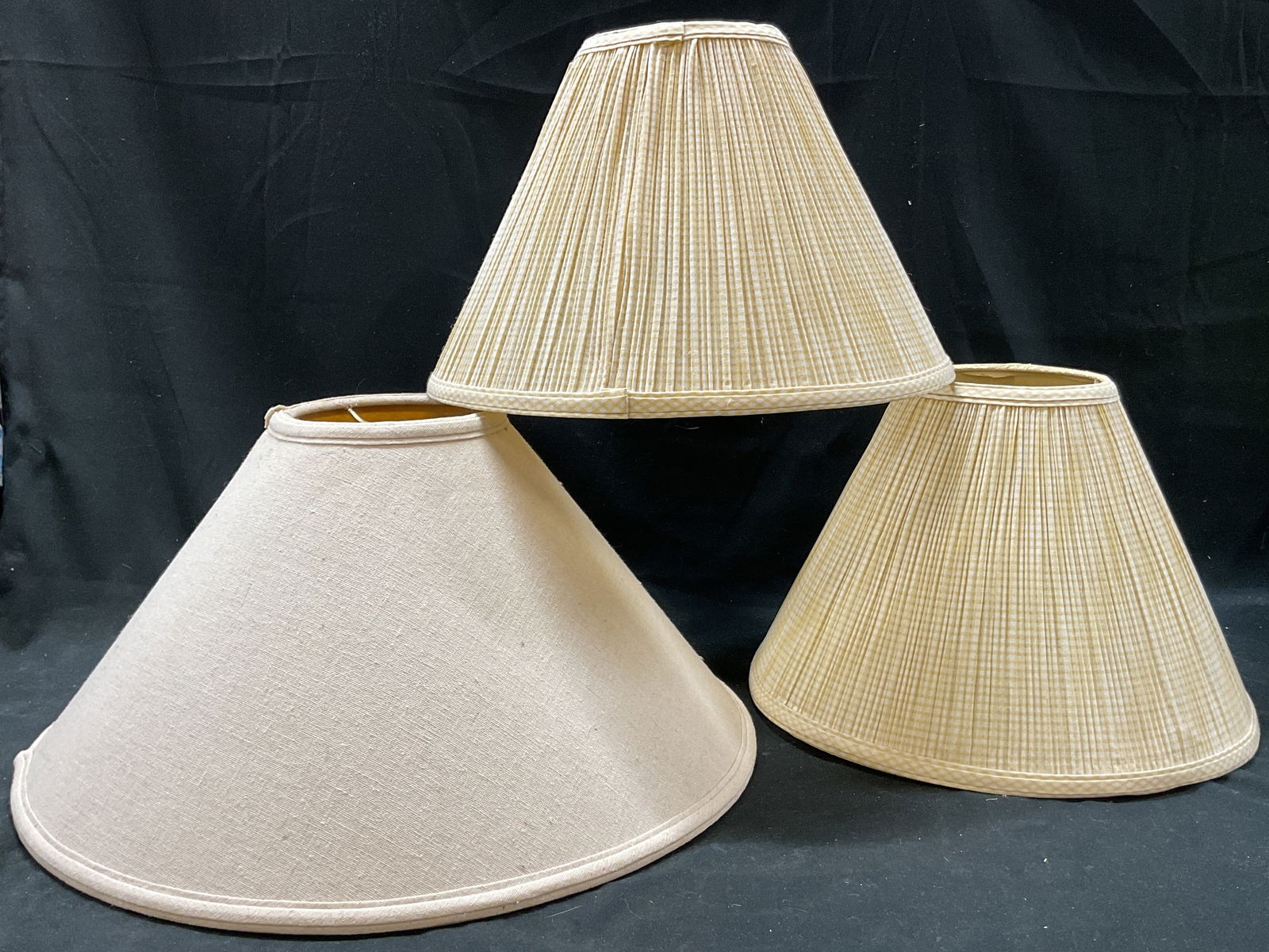 Lot 3 Vintage Fabric Lamp Shades: Lot of 3 vintage fabric lamp shades. Two are yellow and white in a gingham pattern. The other is plain off white. Ribbed textures. Largest measures ht approx 10 inches diam approx 18 inches.