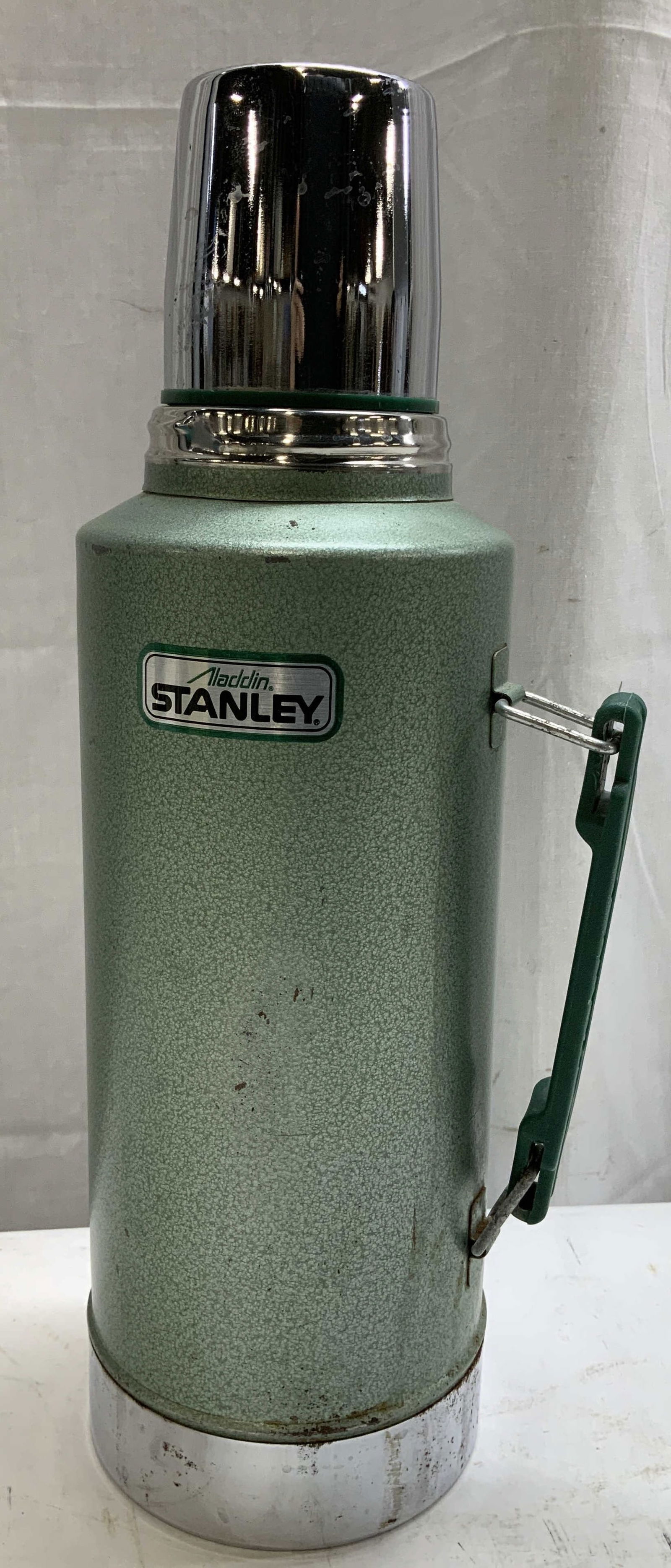 Aladdin Stanley Green & Chrome Vacuum Thermos: Aladdin Stanley No. 945DH features a green finish & chrome finished cup. Metal swing handle. Half gallon. Signed & marked. Reads, ALADDIN STANLEY VACUUM BOTTLE. NO.A945DH. Visible instructions on unde