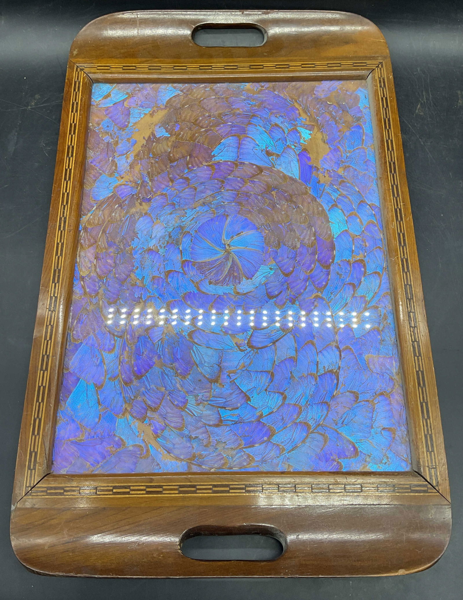 Vintage Wood Butterfly Wing Iridescent Tray: Vintage tray with handles. Center with iridescent purple butterfly wing design. Inlaid wood border. Measure approx 20.75 x 13.25 inches. Back panel is taped. Wear including scratching, losses to desig