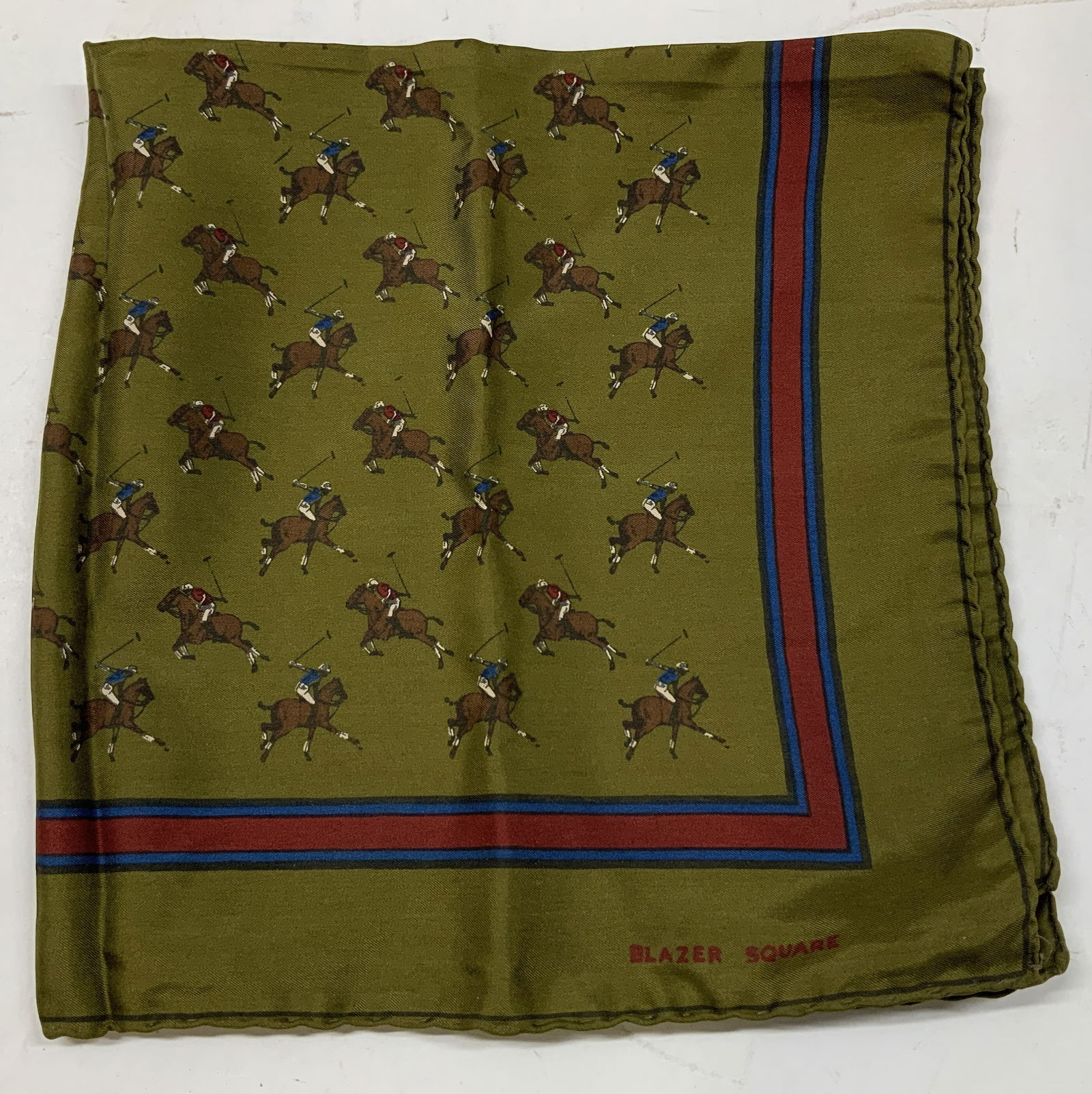 BlazerSquare Silk Pocket Square Polo Players ITALY: Pocket square features an olive tone w a pattern of polo players. Olive, red, brown & blue tones. Signed & marked. Reads, BLAZER SQUARE. ALL SILK. MADE IN ITALY. HANDCRAFT INCORPORATED. Surface wear c
