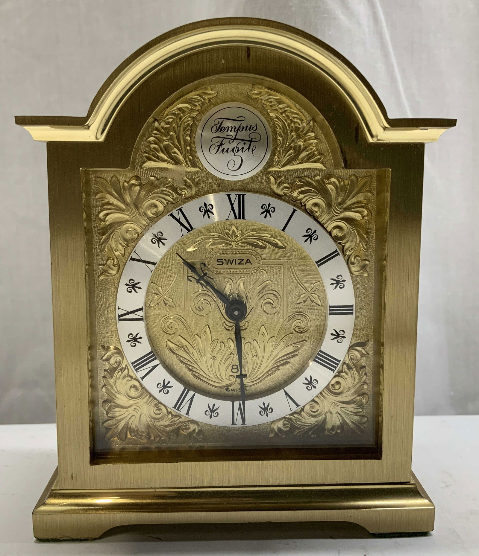 Vtg Swiza Tempus Fugit Brass Alarm Clock SWITZ: Vintage Swiza Tempus Fugit wind-up alarm clock features an ornate interior & Roman numerals. Phrase Tempus Fugit (time flies) reads in interior. Signed & marked. Reads, SWIZA TEMPUS FUGIT. Surface wea