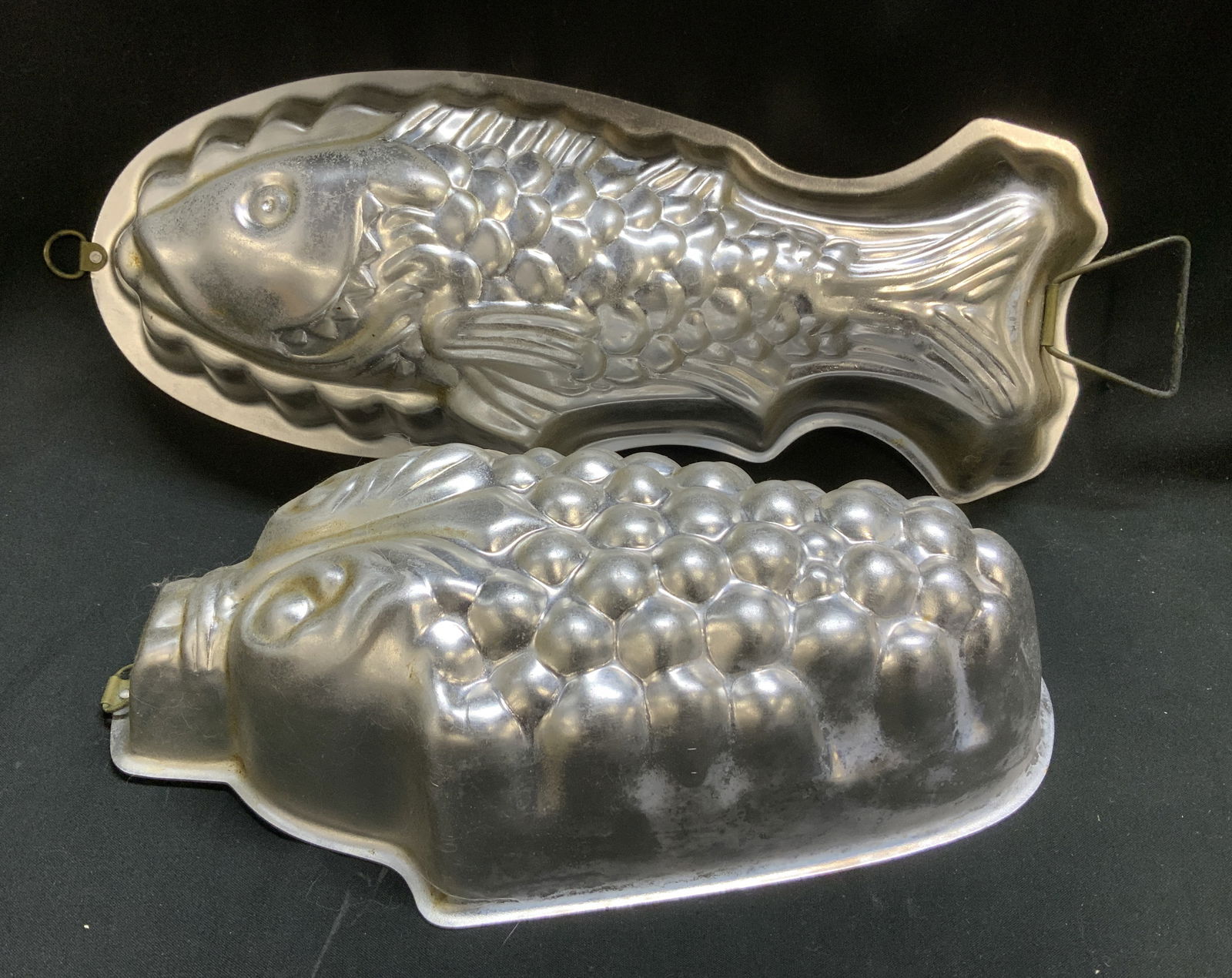 Lot 2 Vtg Silver Toned Fish & Grape Jello Molds: Lot includes, 1 silver toned fish Jello mold & 1 silver toned grape cluster Jello mold. Intricate detailing. Appears to be tin material. Surface wear consistent to age, use & exposure. Measurements: l