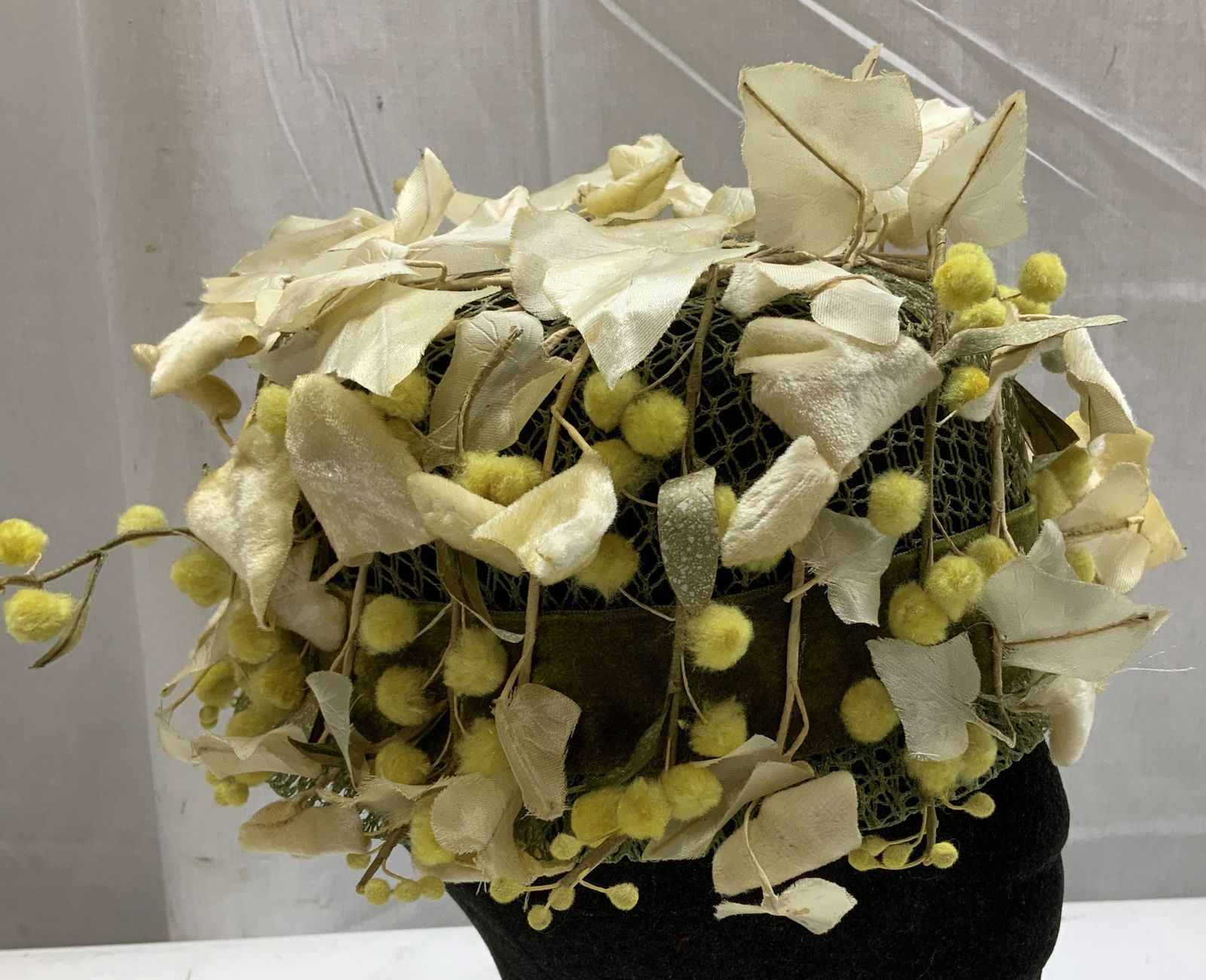 Vntg Best & Co. Fifth Ave Floral Hat NY: Vintage Best & Co. Fifth Avenue floral hat features cream-colored leaves and yellow fuzzy pom-poms on a net base. Fabric & mesh material. Signed & marked on underside. Reads, BEST & CO. FIFTH AVE. NY.