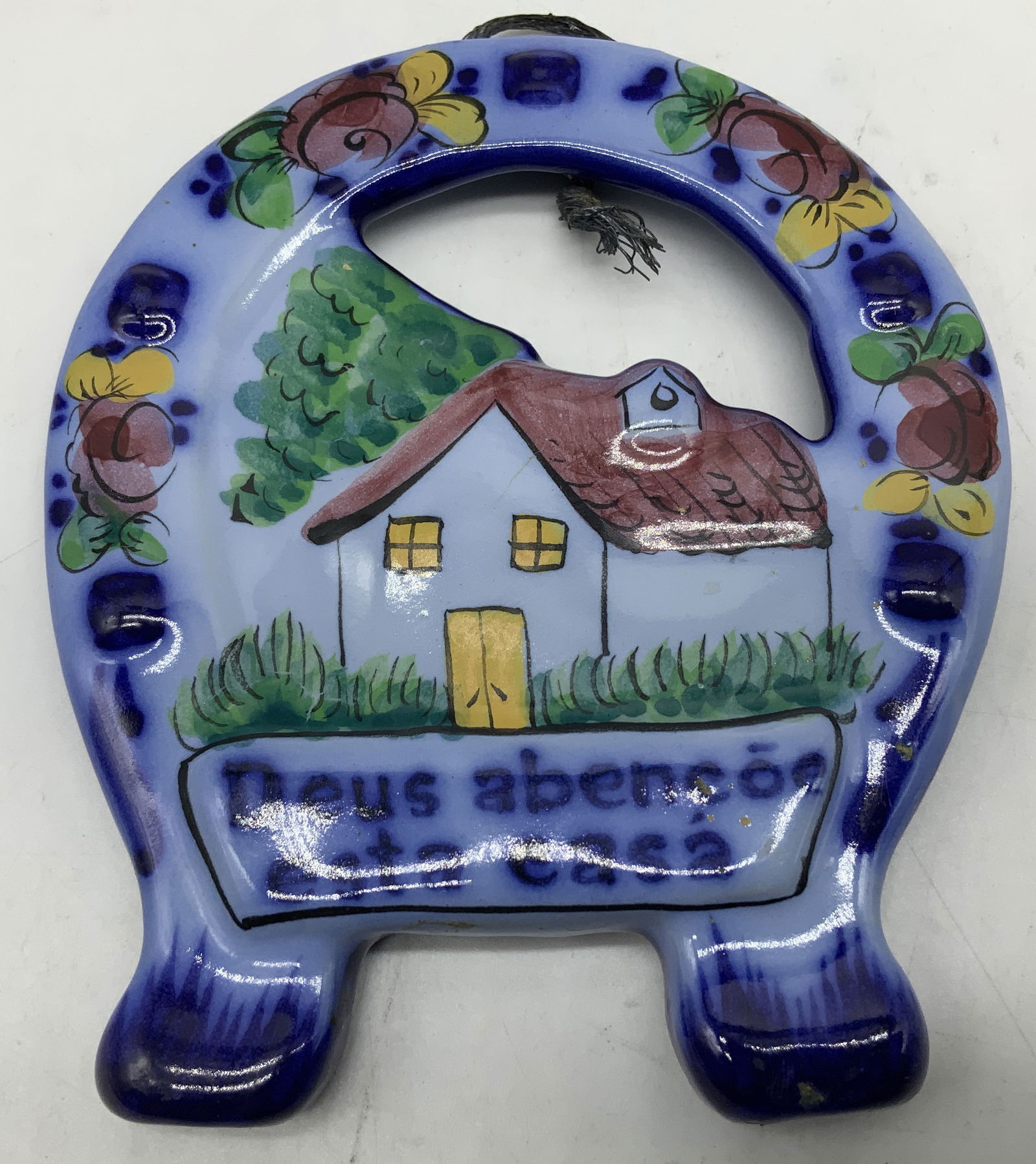 HndPntd Deus Abencoe Esta Casa Wall Decor PORTUGAL: Hand painted ceramic wall decor depicting a scene of a small house with trees & floral border. Center text reads, Deus aben?oe esta casa (God bless this house). Property of opera singers estate from t