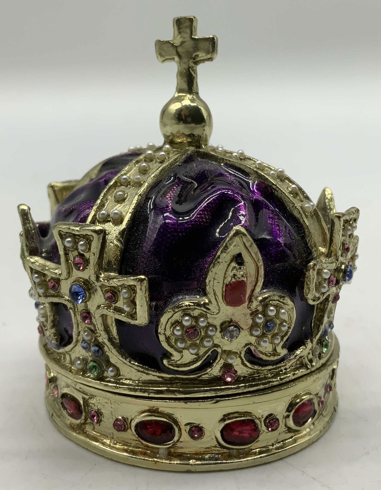 Enameled Rhinestone Crown Trinket Box: Enameled metal trinket box depicts a purple domed top & multicolored rhinestones. Cross finial. Surface wear consistent to age, use & exposure. Measurements: length 2.2in x width 2.2in x height 2.7in.