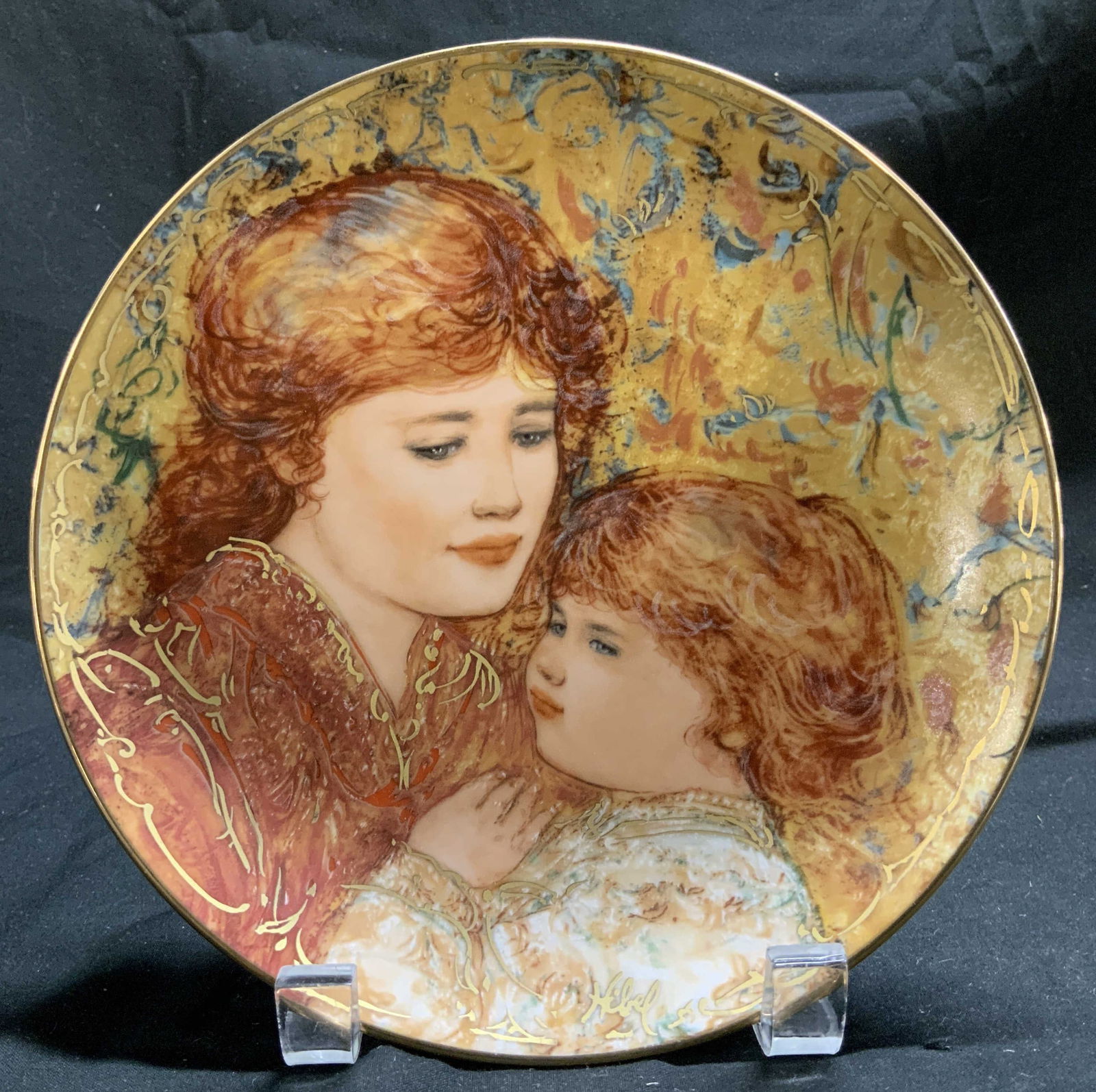 1990 Edna Hibel Compassion Limited Ed Porc Plate: 1990 Edna Hibel limited edition porcelain plate features a mother & child portrait. Gilt accents. Signed & marked on underside. Reads, Compassion first of four in the series Eroica? by Edna