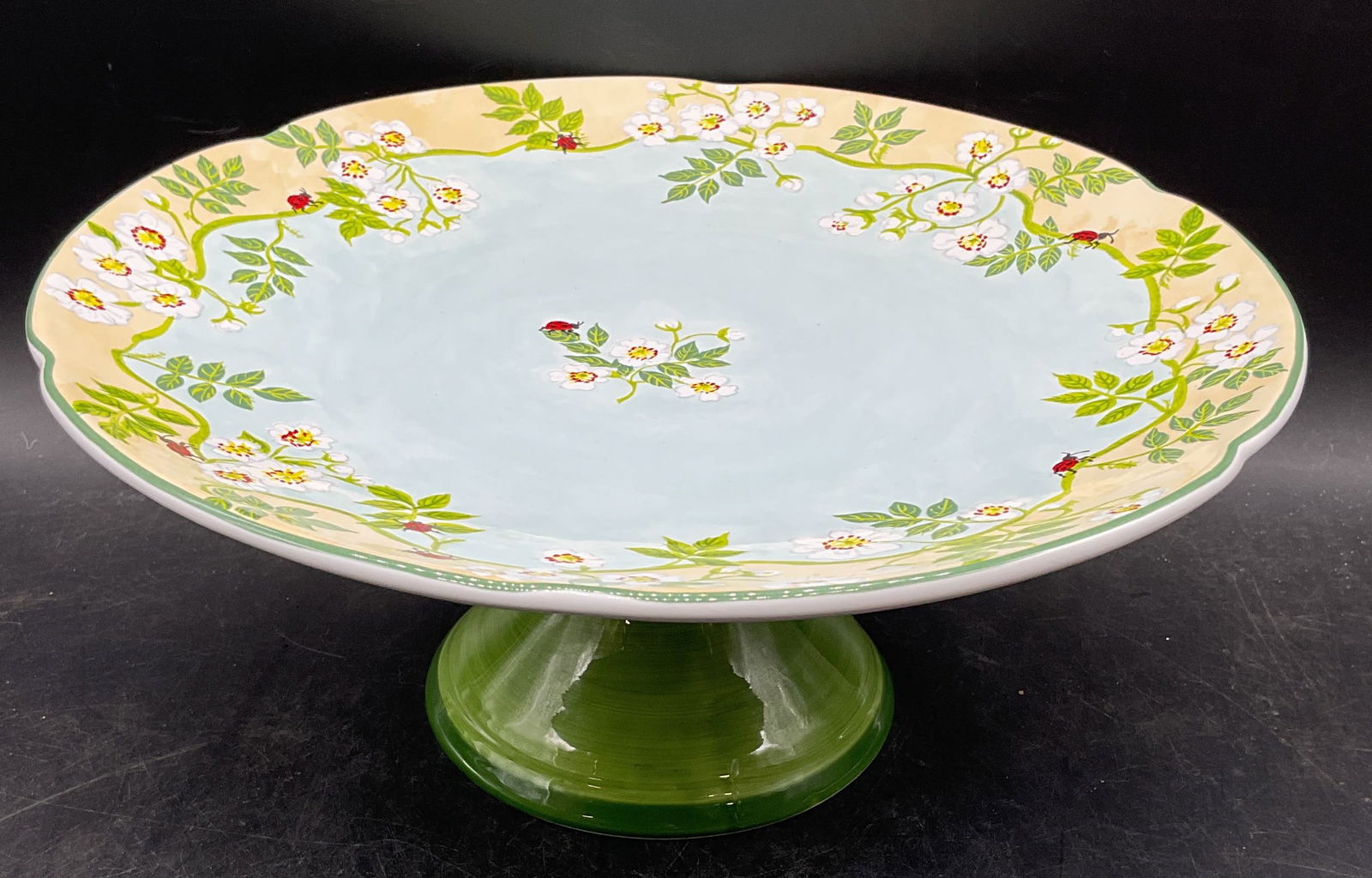 Essex Robins Nest Ceramic Cake Stand: Essex Collection ceramic cake stand in Robins Nest pattern. Floral ladybug design in blue and green. Signed. Made in Portugal. Measures approx 11.75 x 5 inches. Some wear consistent with