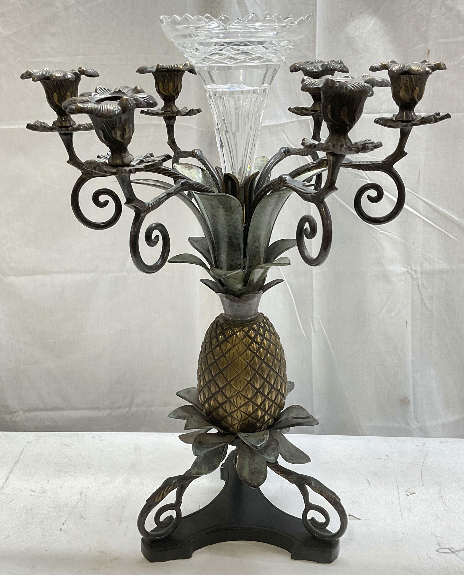 Castilian Bronze Brass Pineapple Candelabra Vase: Signed Castilian Imports bronze and brass pineapple motif candelabra with cut crystal vase. 6 decorative scroll arms with floral sconces. Tripod scroll base. Central crystal fluted sawtooth rim vase.