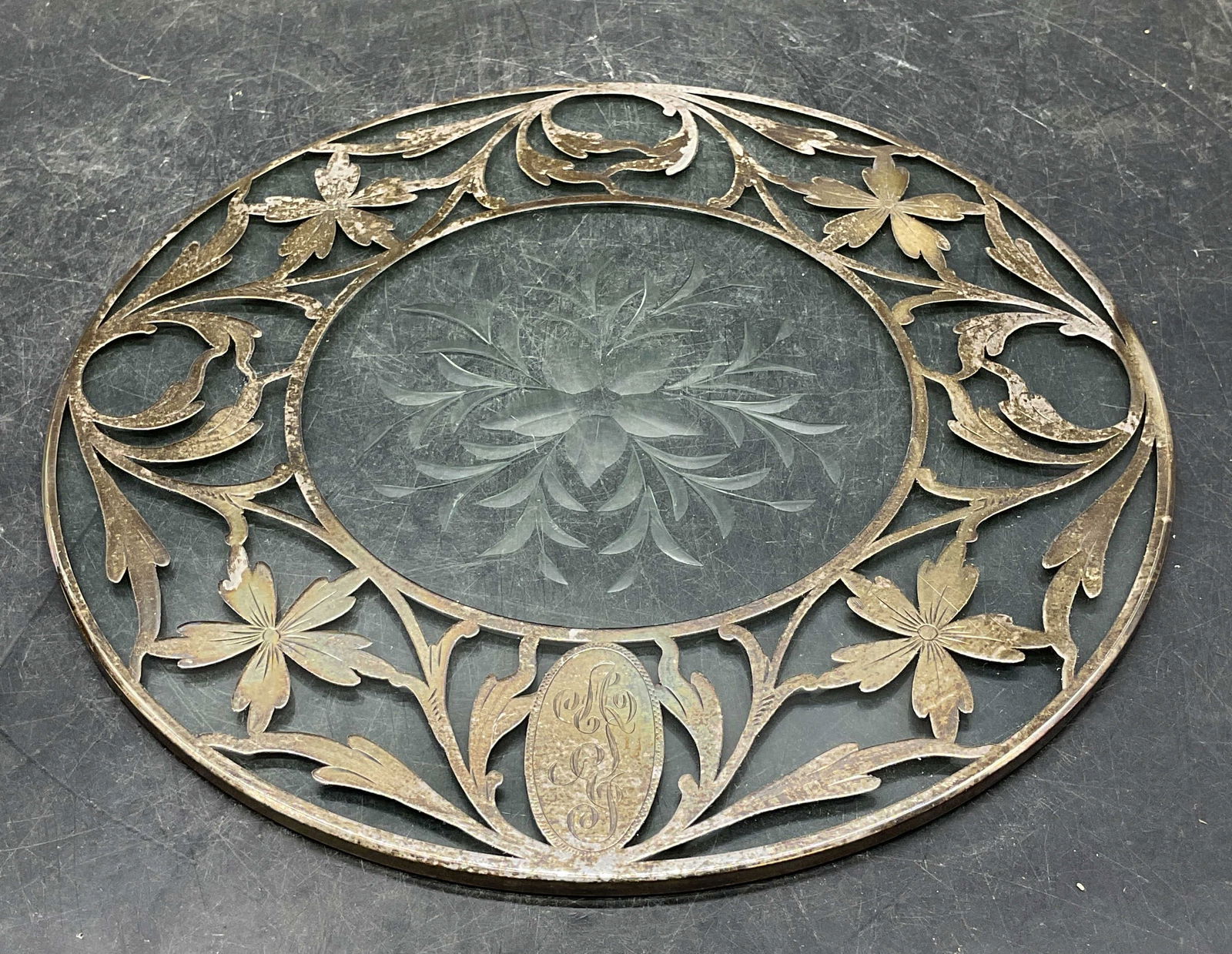 Vintage Sterling Silver Cut Glass Trivet: Vintage cut glass trivet with sterling silver overlay. Monogram engraved on silver. Reticulated floral scroll design. Floral design on glass. Measures approx 8.75 inches wide. Tested for sterling. Wea