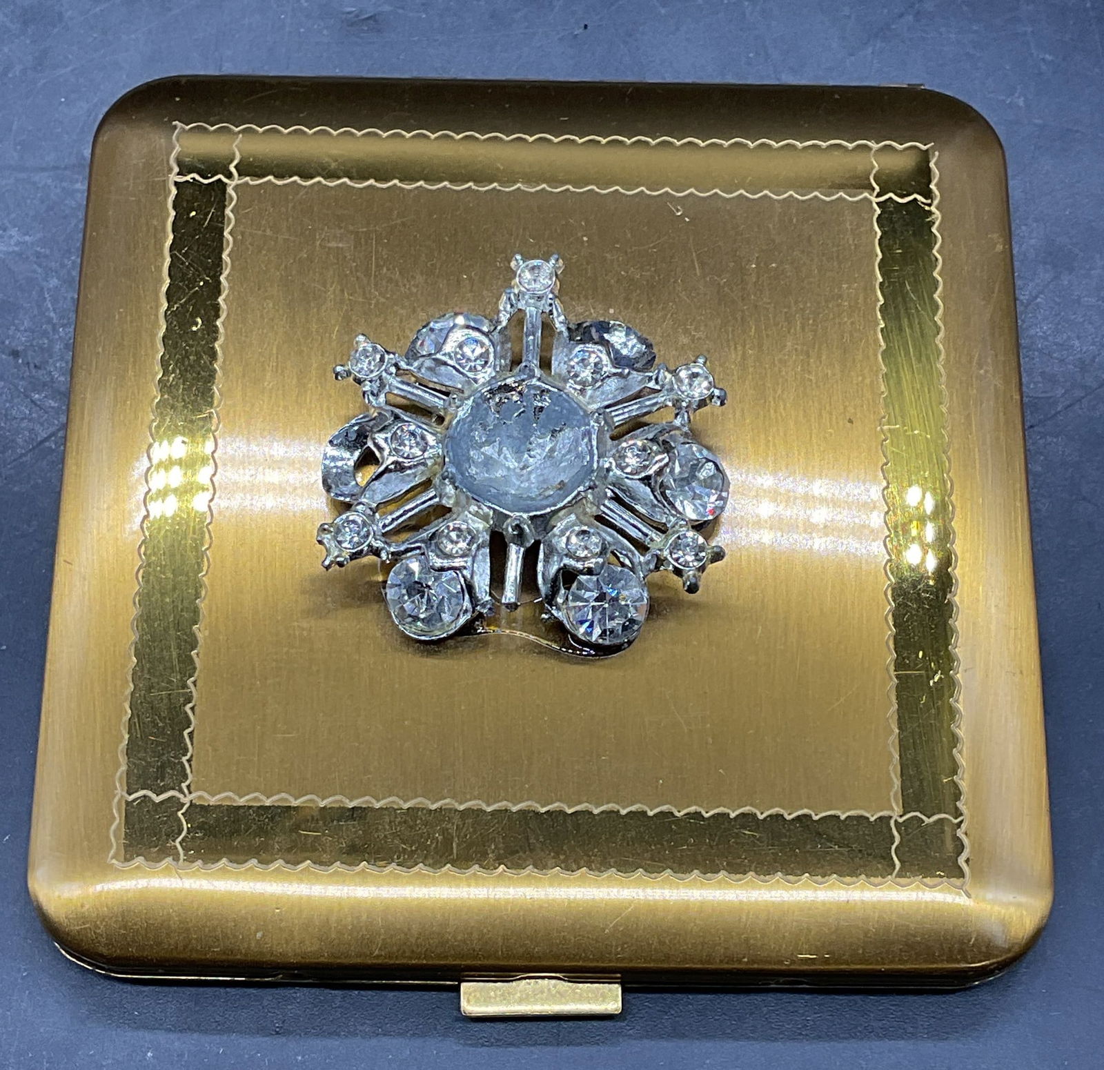 Vtg Dorset Rex Powder Crystal Compact: Vintage signed Dorset Rex Fifth Avenue cosmetic powder compact with mirror. Gold tone with rhinestone decorated cover. Measures approx 3.25 x 3.25 inches. Includes pouch. Some scratching, rhinestones