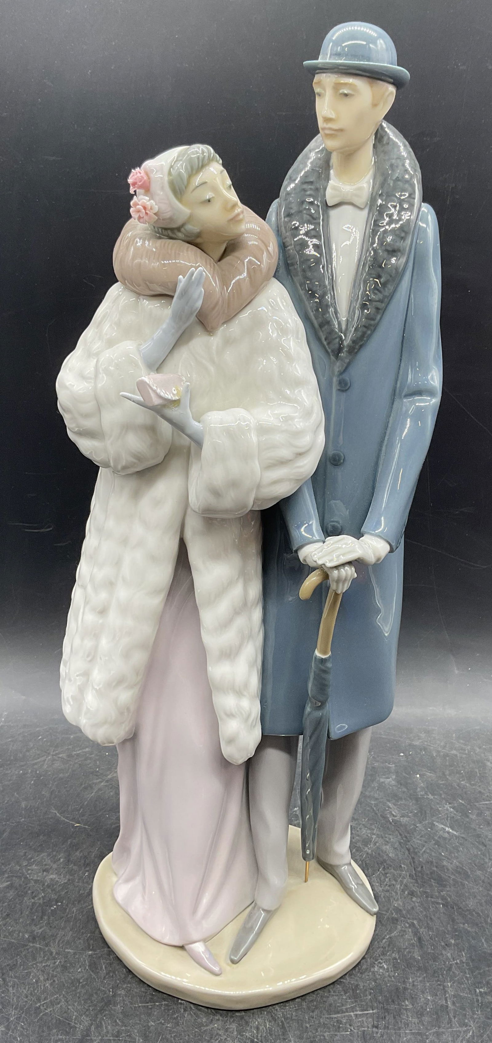 Lladro On The Town Couple Porc Figurine Spain: Lladro On The Town porcelain figurine. Man and woman. Hand painted. Signed. Made in Spain. Measures approx 6 x 5 x 14.75 inches. Some wear consistent with exposure. Lladro, Lladro figurine, on the tow