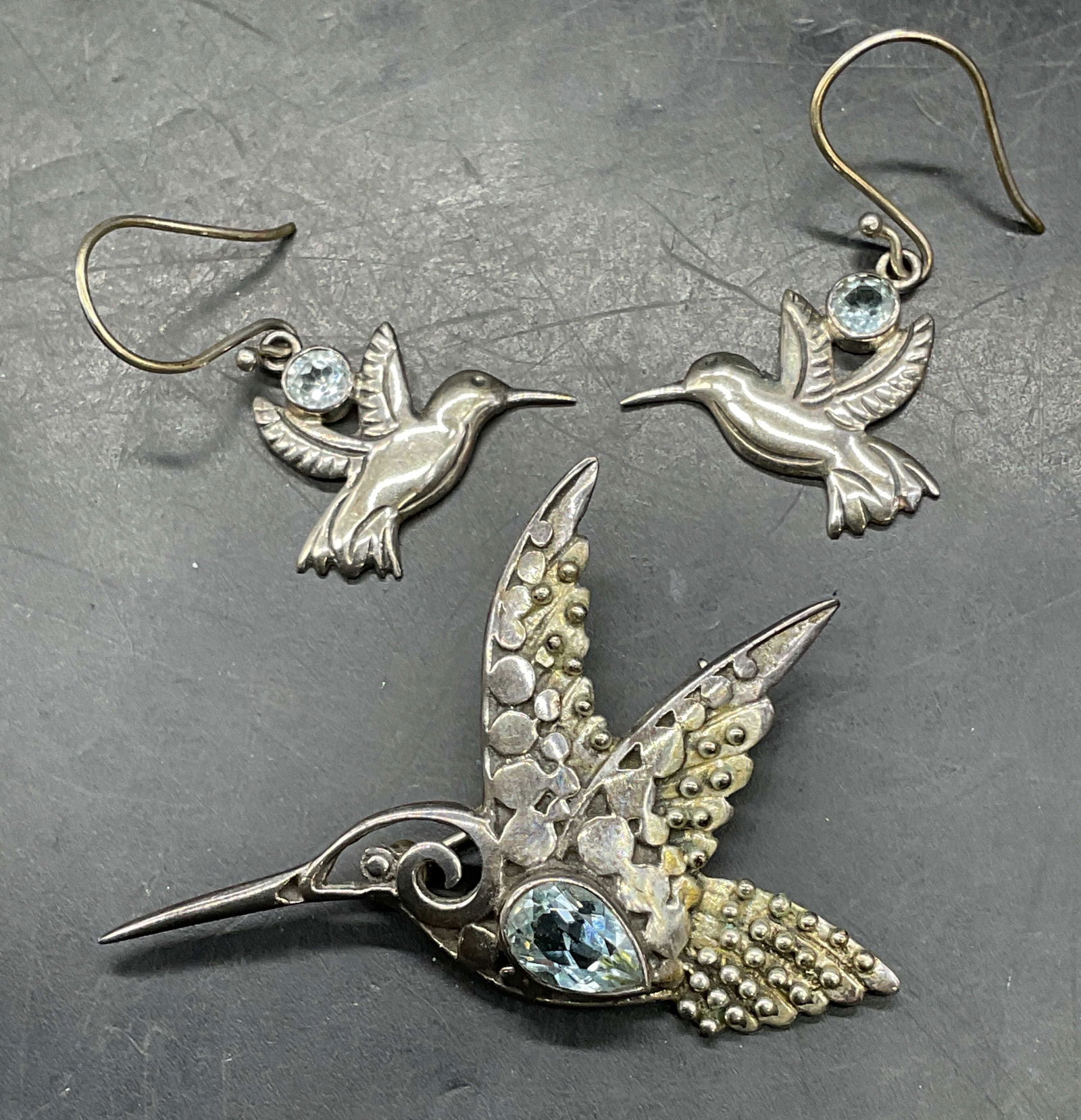 Lot 2 Sue B Sterling Silver Hummingbird Brooch +: Lot of 2 signed Sue B Sterling silver jewelry pieces. Filigree hummingbird brooch with topaz. Hummingbird dangle earrings with topaz. All marked sterling. Brooch measures approx. 1.25 x 2 inches.