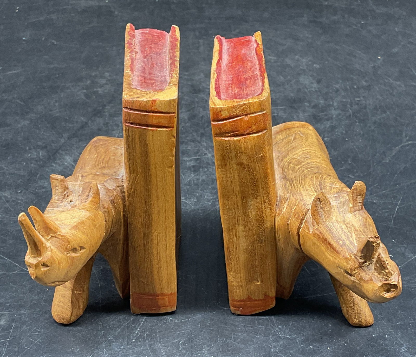 Pair Hand Carved Wood Rhino Bookends, Kenya: Pair of hand carved wood bookends. Rhinoceros and book motif. Made in Kenya. Measures approx. 4.5 x 2 x 3.75 inches. Some scratching. Bookends, rhinoceros bookends, wood bookends, decorative arts, hom