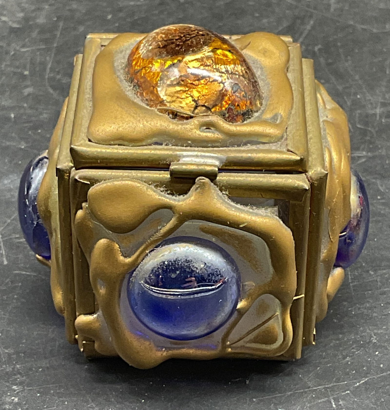 Vintage Gold Tone Glass Trinket Box: Vintage gold and silver tone metal with blue and iridescent gold tone glass cabochons. Measures approx. 2 x 2 x 1.75 inches. Wear including scratching. Trinket box, glass trinket box, gold tone trinke