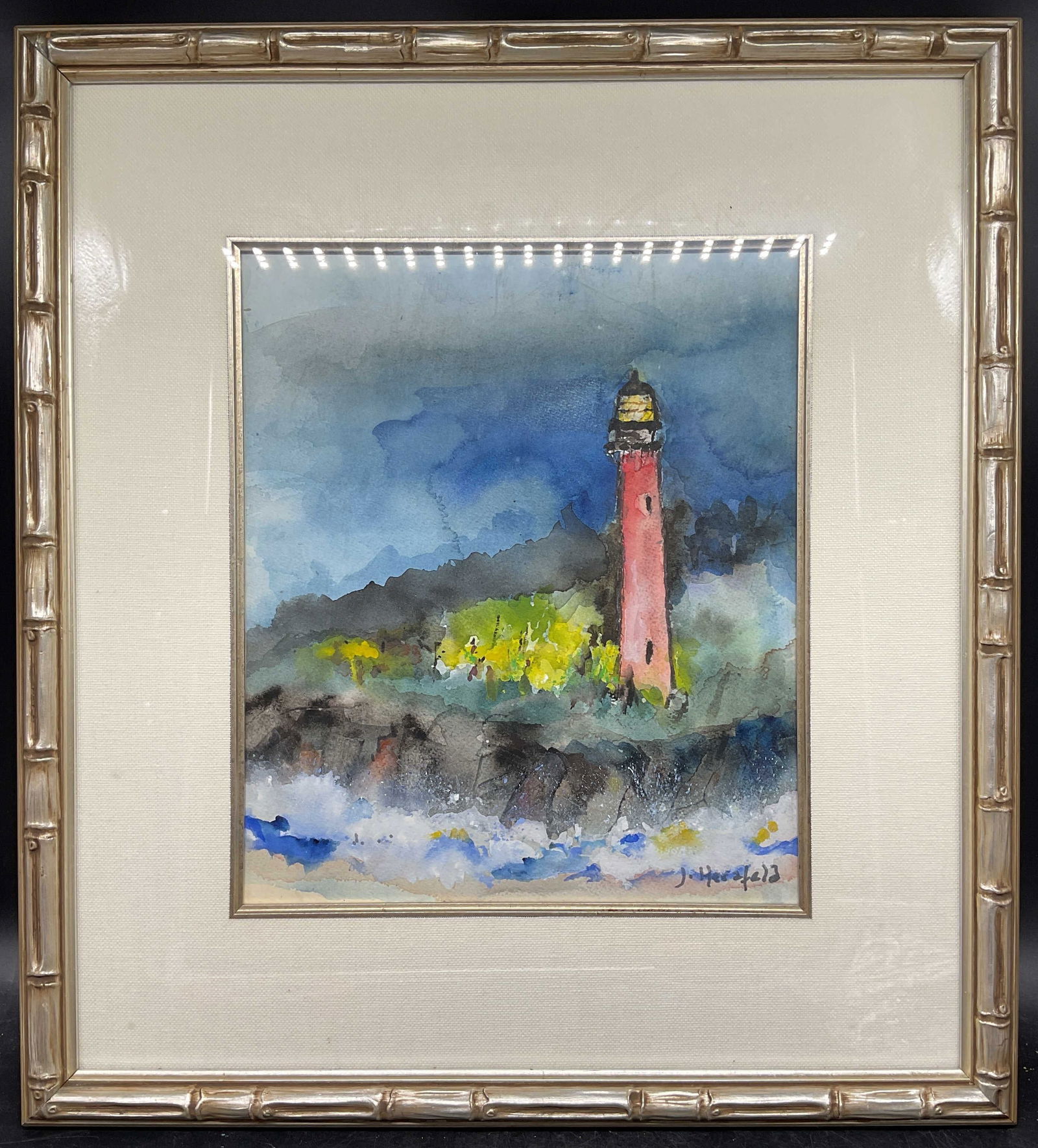 Signed Herzfeld Lighthouse Watercolor Painting: Framed and matted watercolor painting. Signed lower right, possibly J Herzfeld. Abstracted view of a red lighthouse with landscape. Silver leaf bamboo motif frame. Not examined out of frame. Frame mea