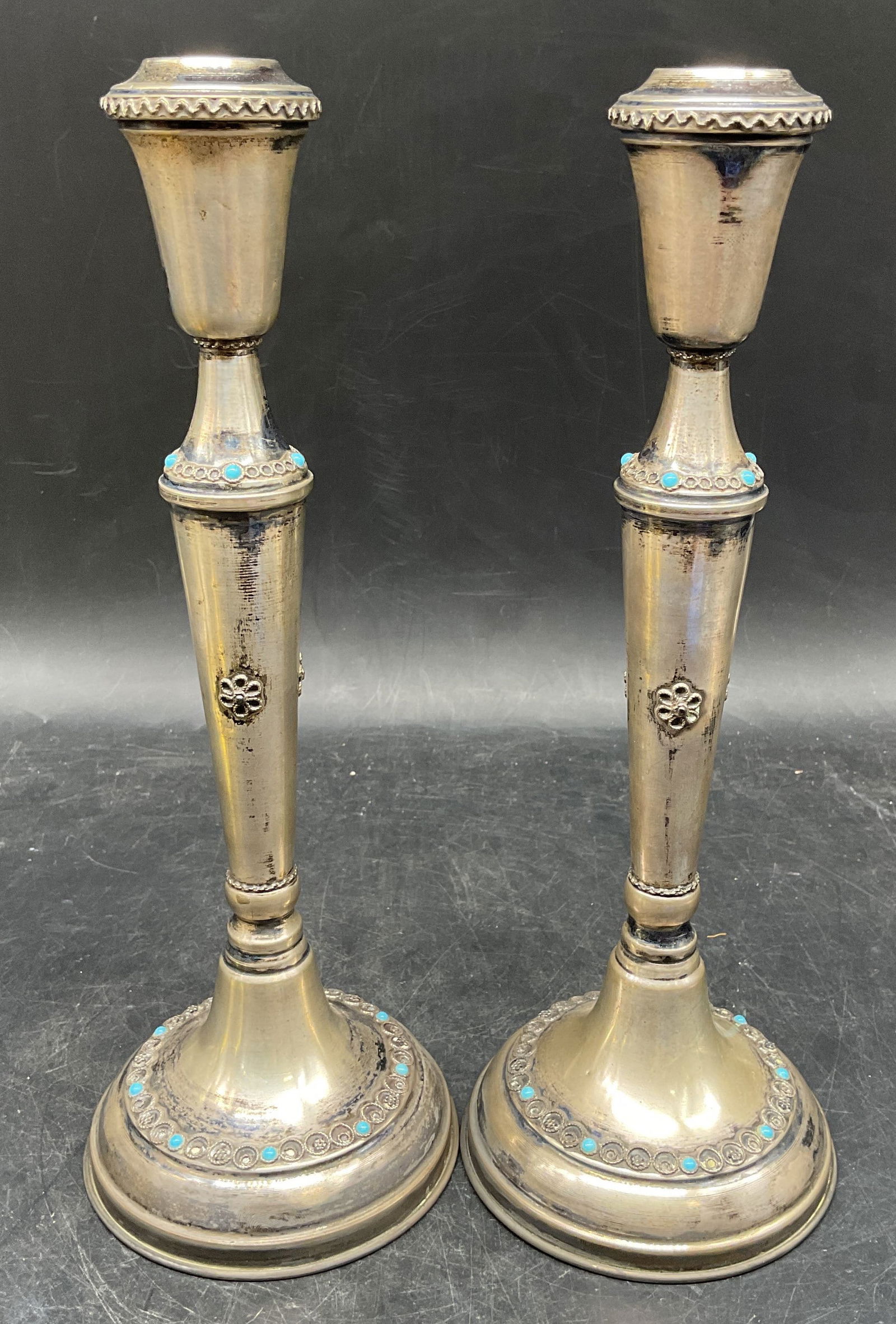 Pair Sgn Sterling Silver Turquoise Candlesticks: Pair of signed vintage sterling silver candlesticks with turquoise cabochons. Filigree floral and circle designs. Marked sterling. Signed illegibly. Measures approx. 3.75 x 10.5 inches. Total